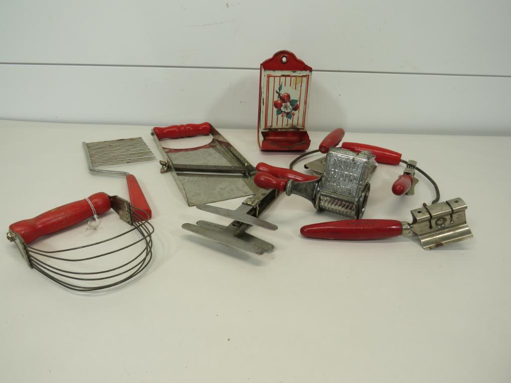 Vintage Red Handled Kitchenware: A total of ten pieces, including slicer, mixer, graters, cake knife, match safe, potato peeler and more. Showing wear due to usage and age as seen in photos. 