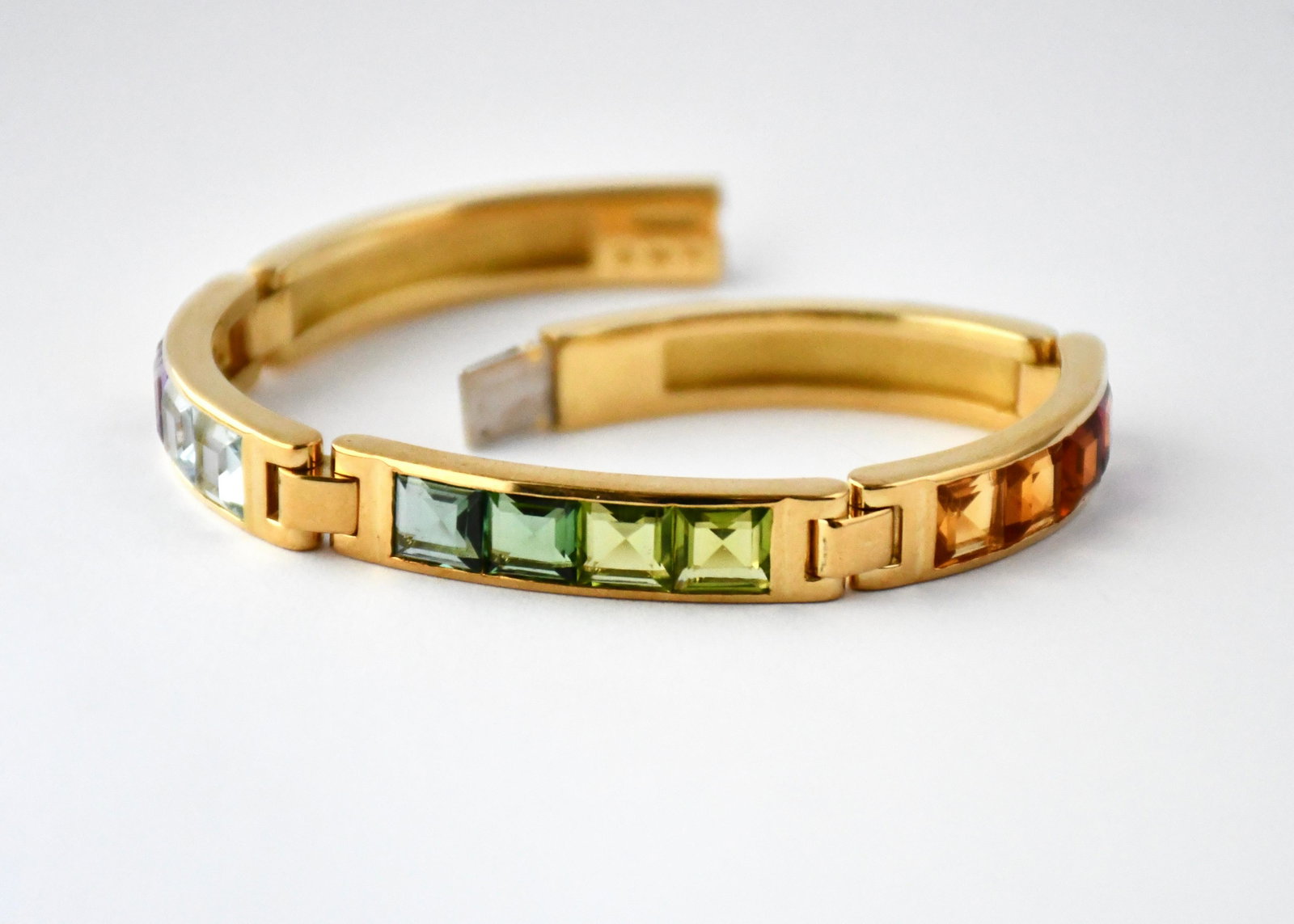 18kt Yellow Gold and Multi-gem Lady’s Bracelet, L. 6.5”: Five-link yellow gold bracelet set with approx. 12 square cut colored gemstones measuring approx. L. 5mm, W. 5mm each, press-clasp, stamped Â“SWISSMADEÂ”, Â“18KÂ” and Â“750Â” with un