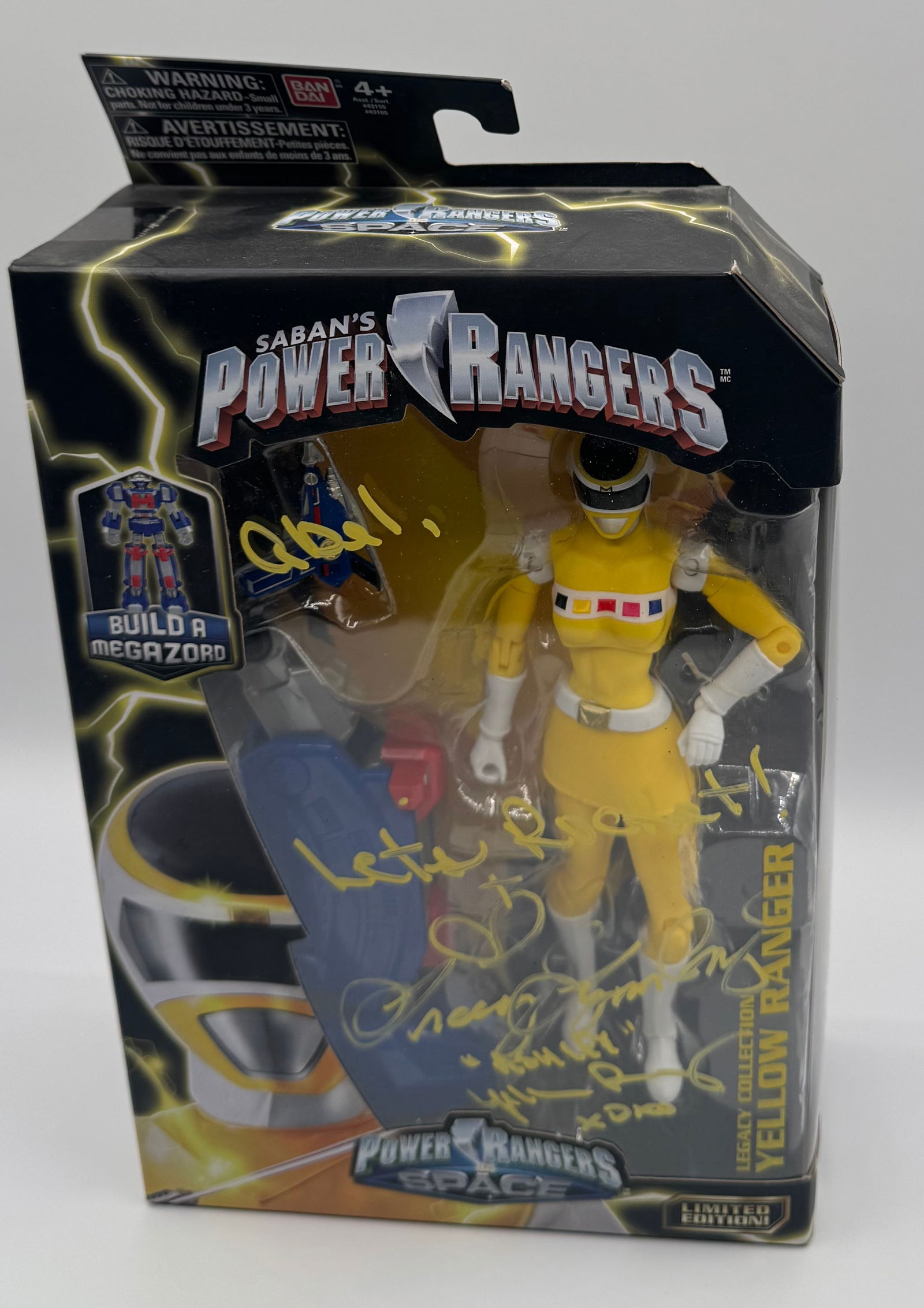 Power Rangers In Space Yellow Ranger Figure – Signed by Tracy Lynn Cruz: A Legacy Collection Yellow Ranger figure hand-signed on the packaging. • Signature: Authentically signed in yellow ink by Tracy Lynn Cruz ("Ashley Hammond") with "Let's Rocket!"