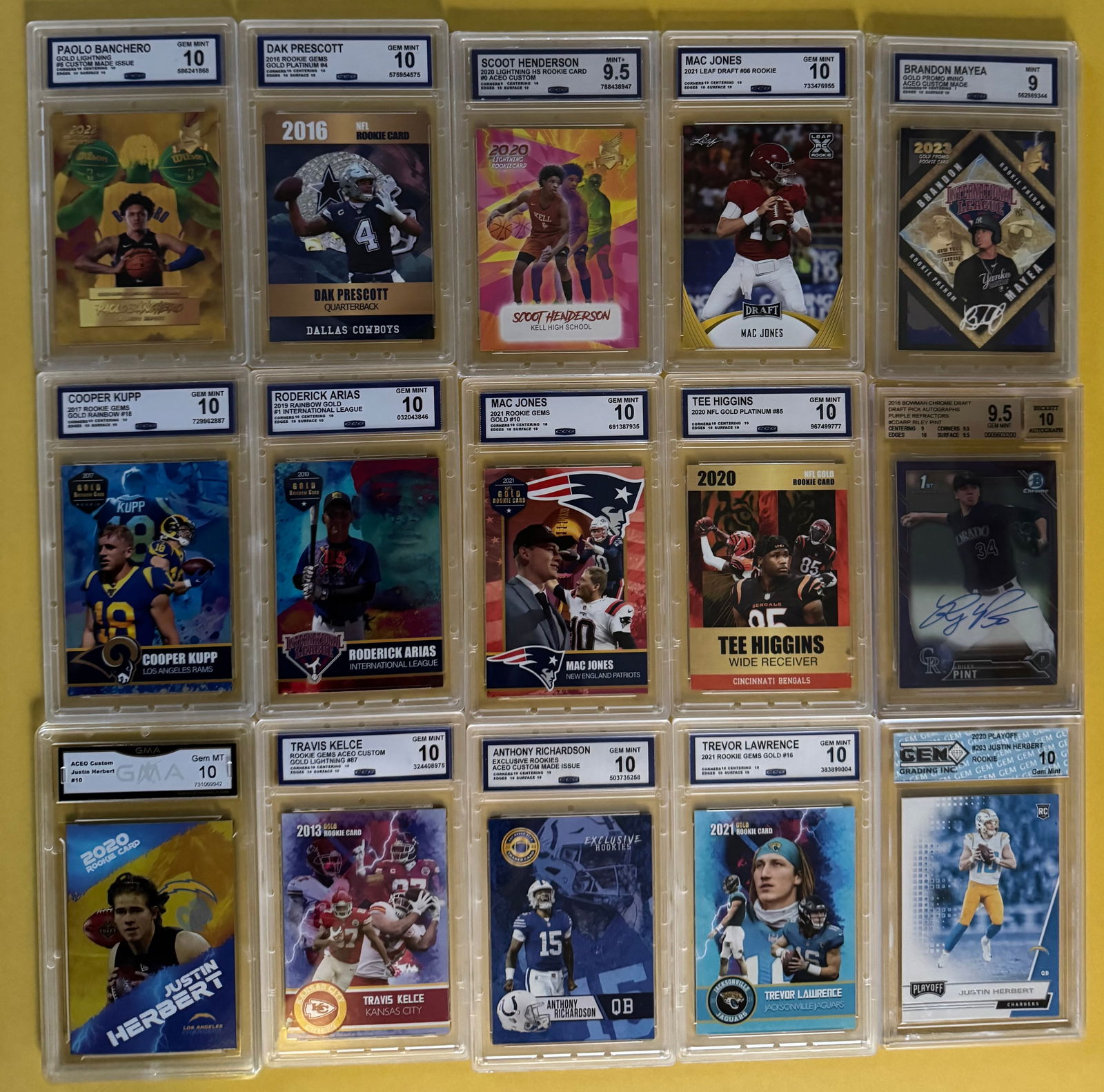 (15) Sports Cards - Paolo Banchero, Dak Prescott, Trevor Lawrence, Mac Jones & More: This lot features a collection of 15 graded modern sports cards across football, basketball, and baseball. These cards are presented in custom-designed "Rookie Gems" and "Lightning Gold" limited editi