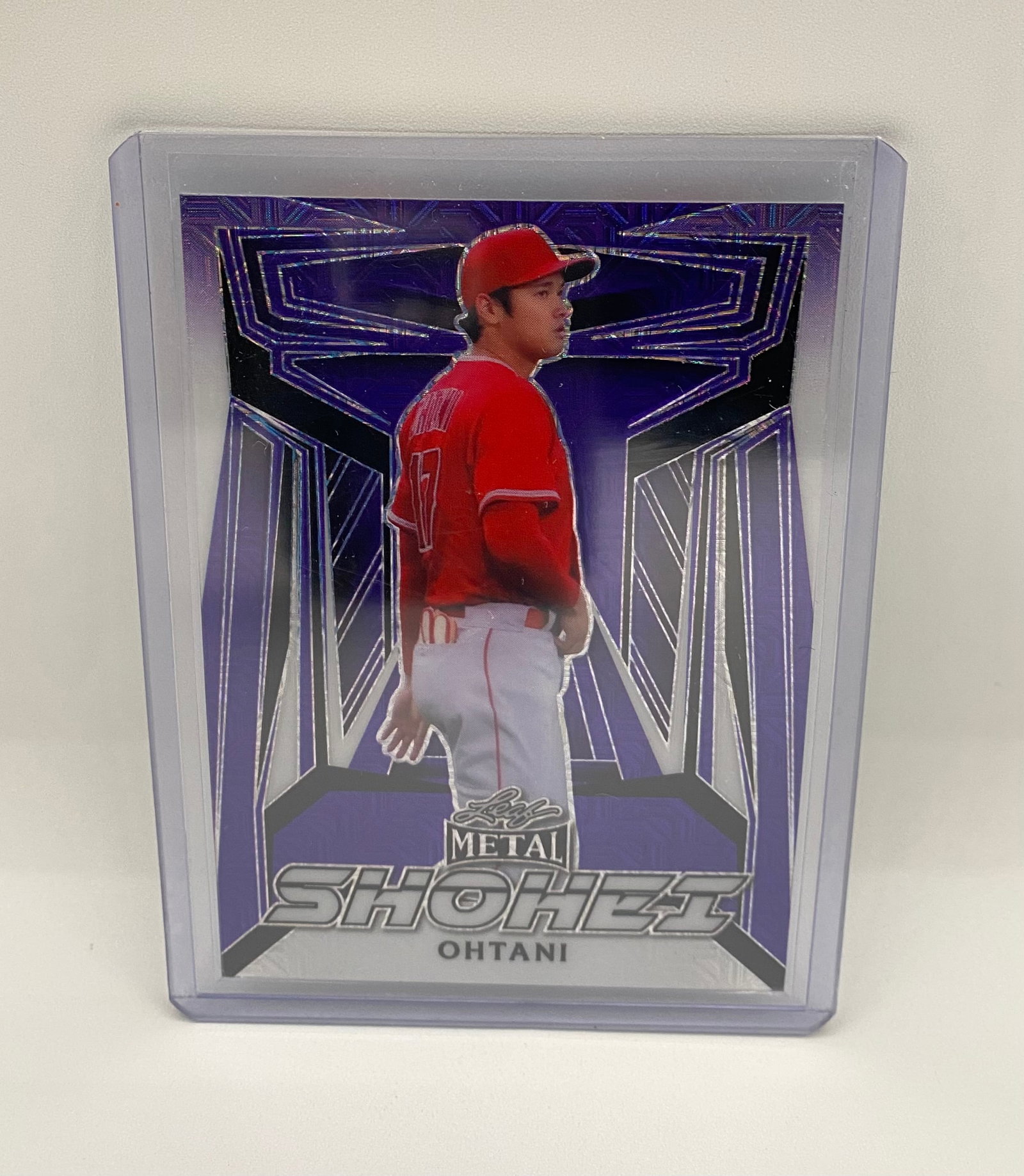 Shohei Ohtani Leaf Metal Purple Parallel – Sharp in Top Loader /9: A visually striking Shohei Ohtani Leaf Metal card featuring a vibrant purple geometric background. The card is presented in a protective top loader and appears to be in excellent condition. Great