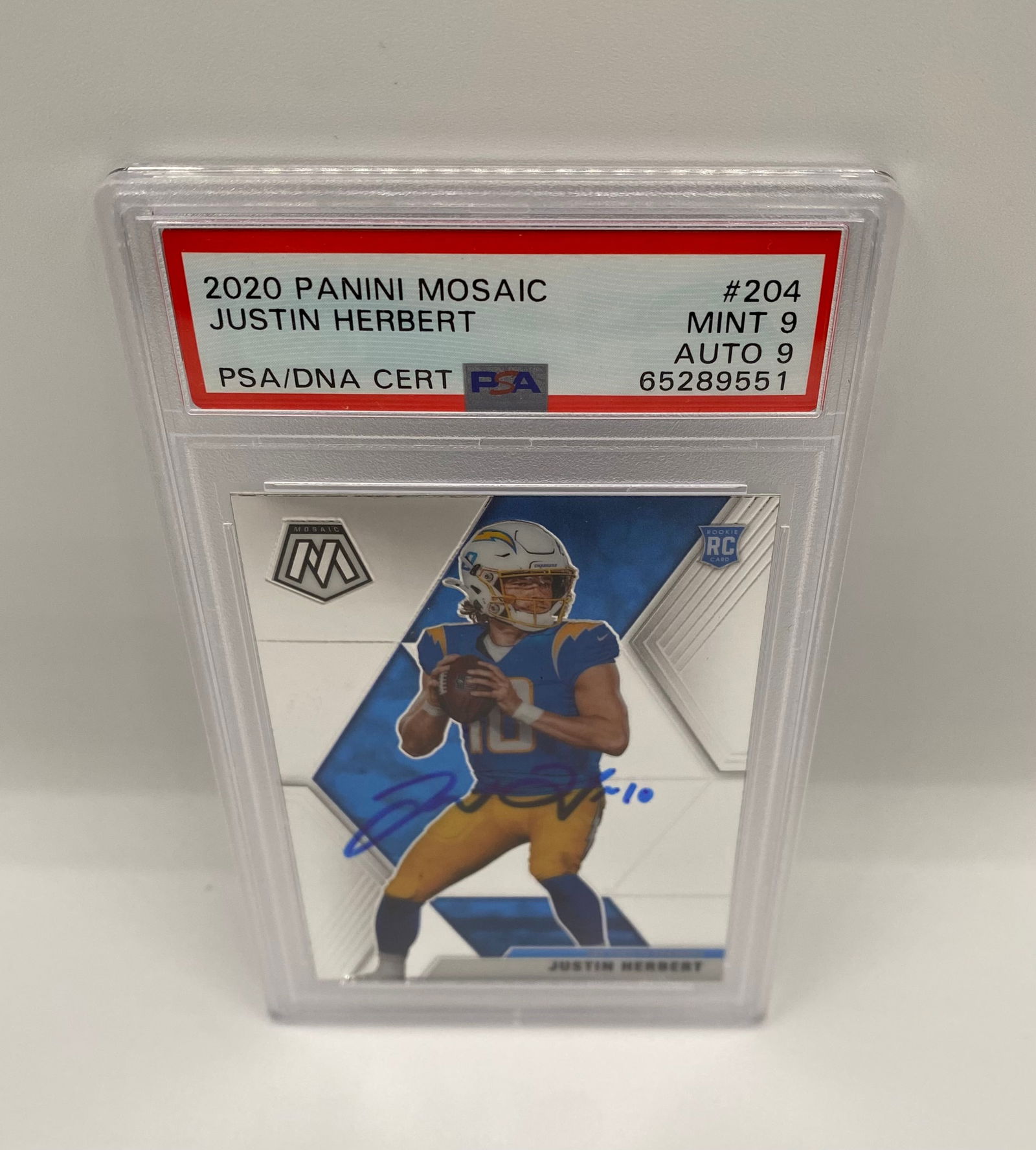 2020 Panini Mosaic Justin Herbert #204 Rookie AUTO - PSA 9 / AUTO 9: A premier rookie card of Chargers QB Justin Herbert featuring an On-Card Blue Ink Autograph. Dual-graded by PSA with a MINT 9 for the card and a 9 for the Auto. Includes the PSA/DNA Certification for