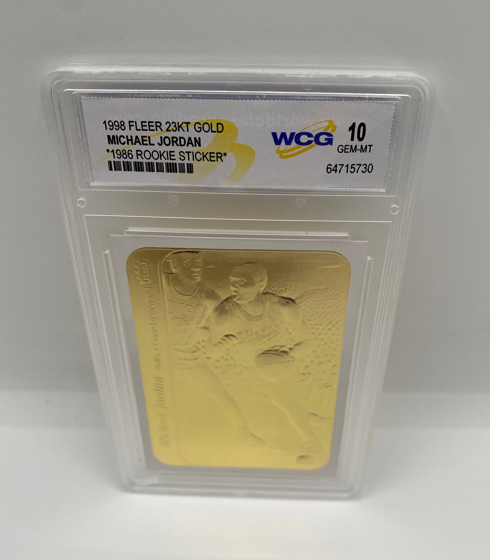 1998 Fleer Michael Jordan 23KT Gold 1986 Rookie Sticker Tribute - WCG 10 Gem-MT: A 23KT gold leaf tribute to the most famous basketball sticker of all time: the 1986 Fleer MJ Rookie Sticker. Sculpted in gold and graded WCG 10 Gem-MT. 