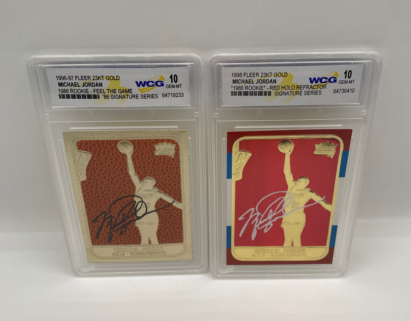 (2) Michael Jordan 1986 Rookie Tribute 23KT Gold Cards - WCG 10 Gem-MT: Card 1: 1996-97 Fleer 23KT Gold "Feel the Game" Signature Series. • Card 2: 1998 Fleer 23KT Gold "Red Holo Refractor" Signature Series. • Details: Both cards feature facsimile (printed)