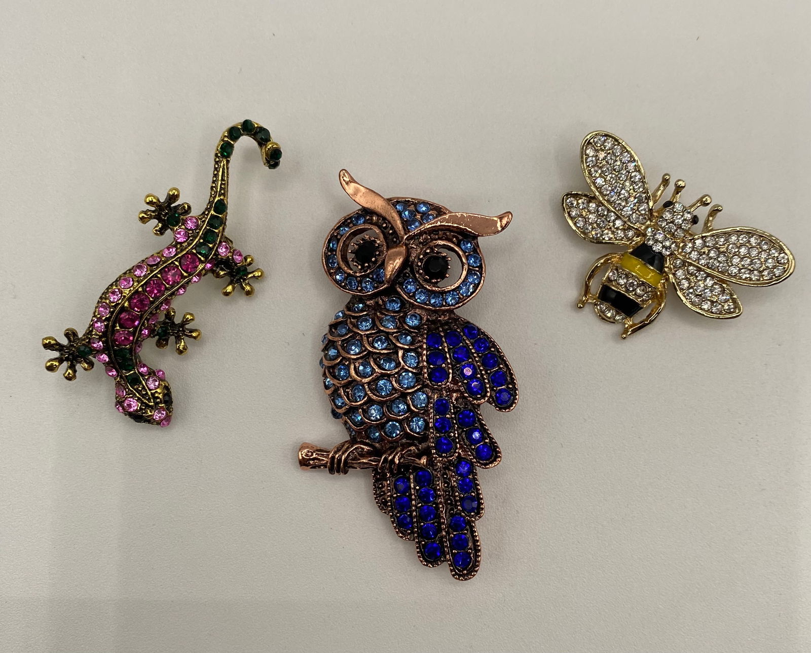 Vintage Whimsical Animal Brooch Lot - Blue Rhinestone Owl, Pink Gecko, & Crystal Honey Bee: A delightful trio of vintage-style animal figural brooches. This lot features vibrant enamel work and sparkling rhinestone pavé settings, ranging from antique copper tones to bright gold finishes