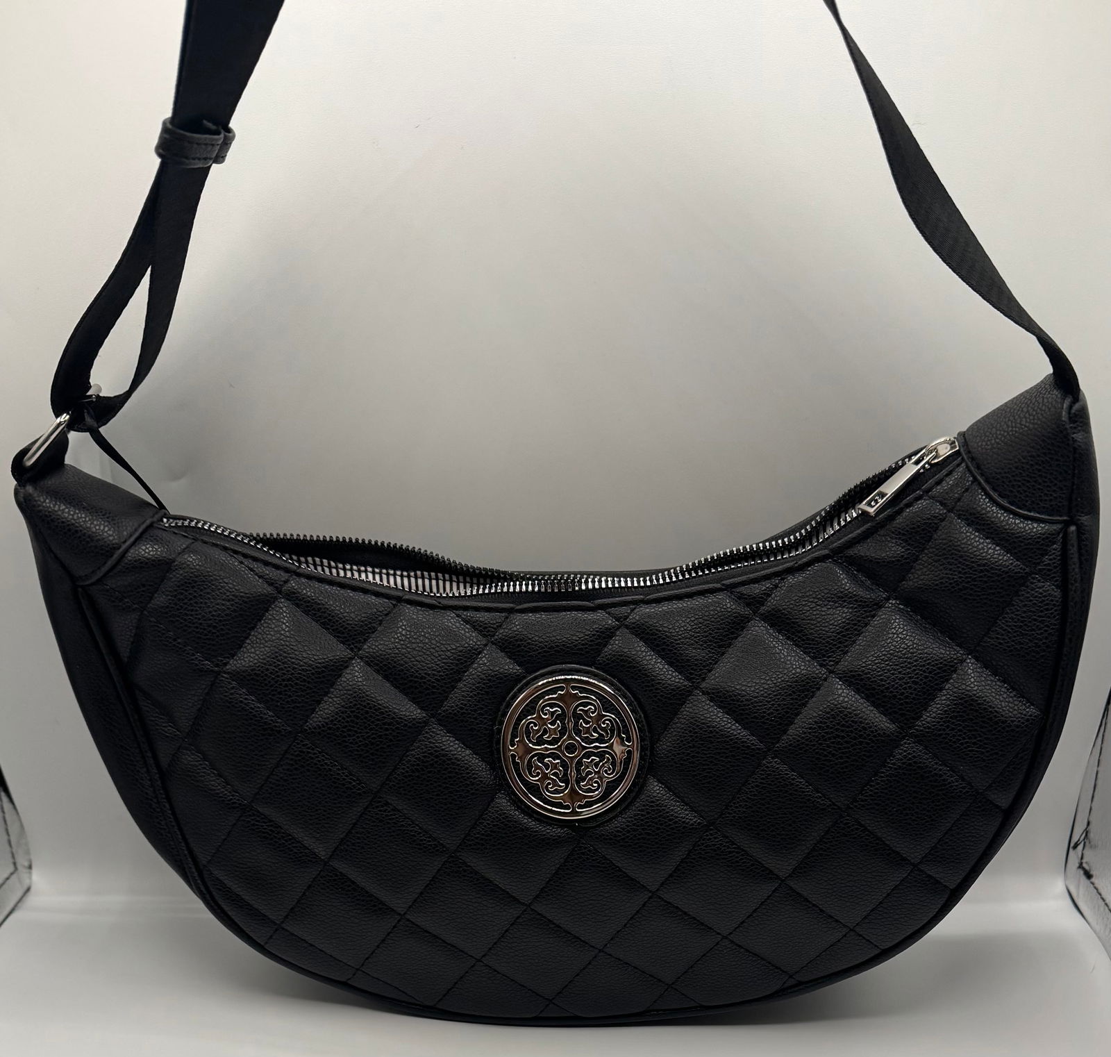 Quilted Black Crescent Vegan Leather Shoulder Bag: Elevate your accessory collection with this sleek and modern crescent-shaped shoulder bag. Crafted from high-quality, pebble-textured vegan leather, this piece features a sophisticated quilted