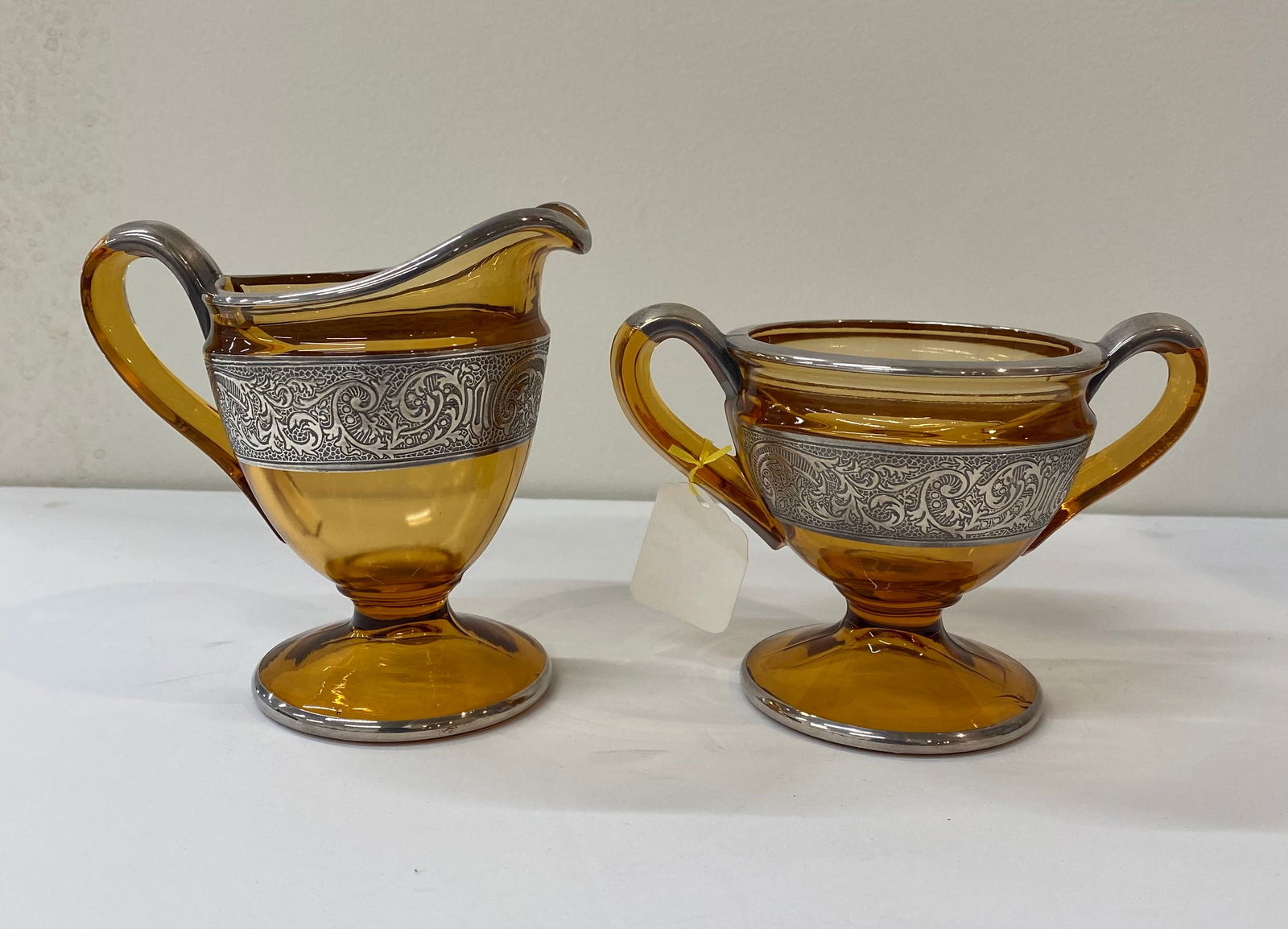 Vintage Amber Glass Creamer & Sugar Set with Filigree Sterling Silver Overlay: This is a stunning two-piece vintage serving set featuring a footed creamer and a double-handled open sugar bowl. The set is crafted from rich, honey-toned amber glass and is elegantly decorated with