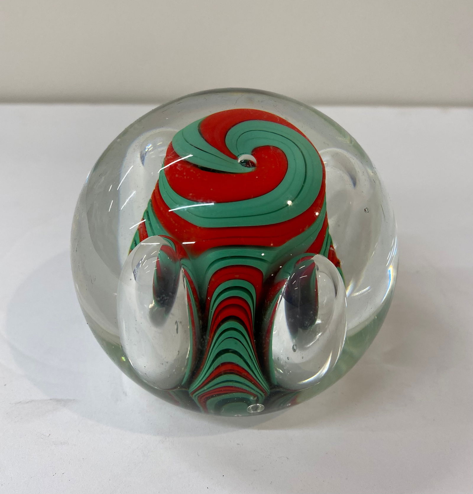 Murano Art Glass "Wig-Wag" Ribbon Paperweight: A striking clear glass paperweight featuring a central "wig-wag" or ribbon swirl design in festive red and mint green. The internal core is surrounded by several large, intentionally placed controlled