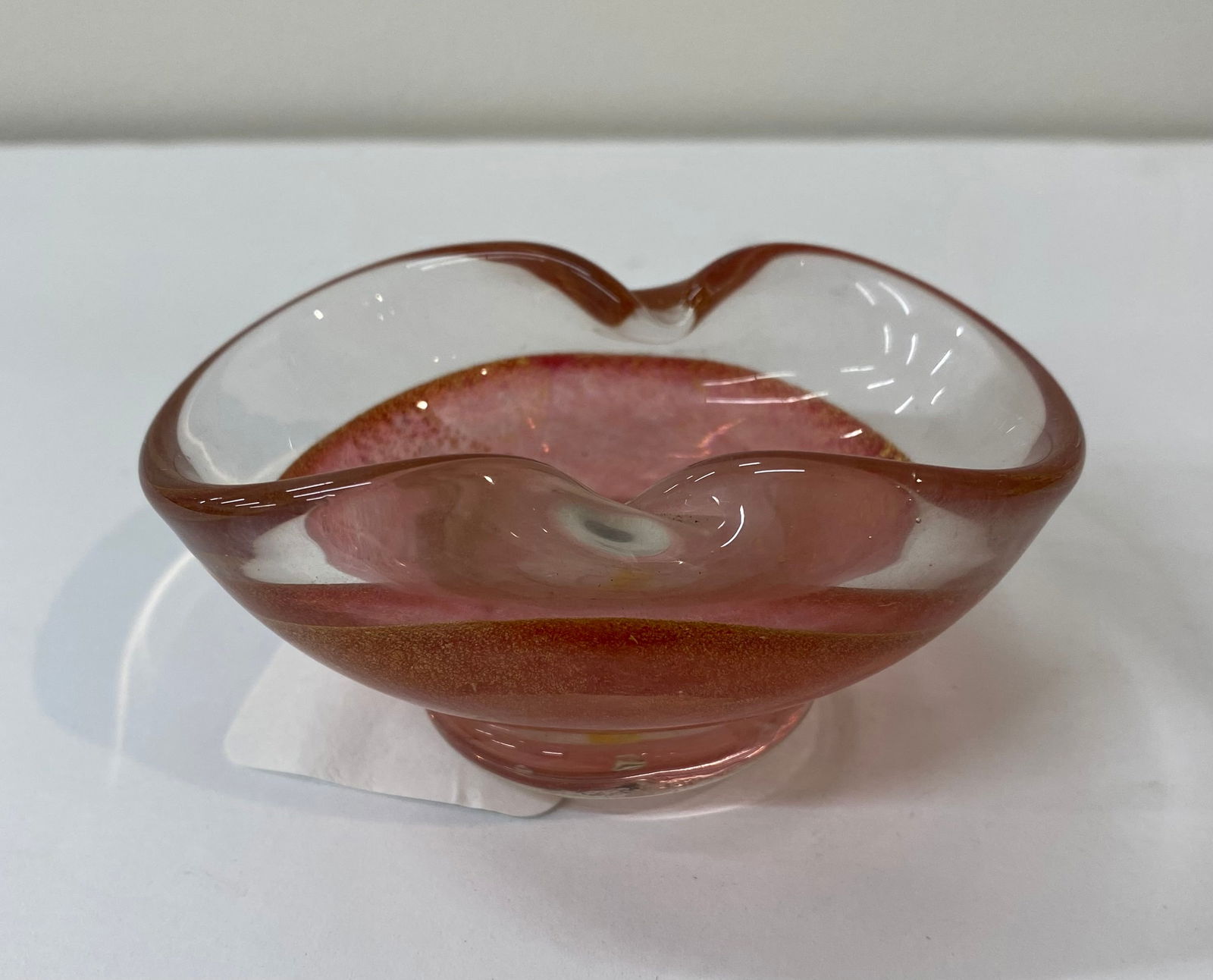 Mid-Century Murano Style Art Glass Bowl - Pink Cased Glass with Gold Aventurine: An elegant, organic-shaped art glass bowl. The piece features a soft pink interior infused with heavy gold-tone "aventurine" flecks, encased in a thick, clear glass layer. • Material: Cased