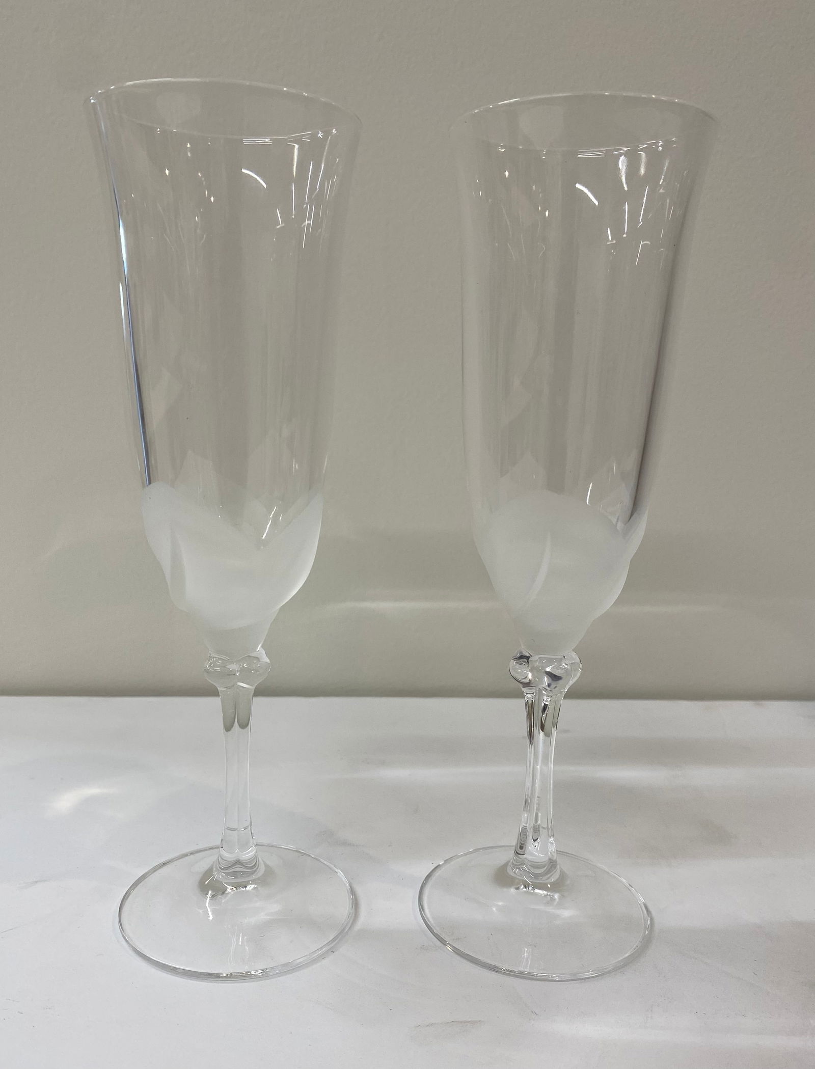 Pair of Frosted "Petal" Crystal Champagne Flutes - Stemware: A romantic pair of champagne flutes with a unique botanical motif. • Design: The base of the bowl features a frosted, molded "leaf" or "petal" design transitioning into a clear tulip-shaped rim.