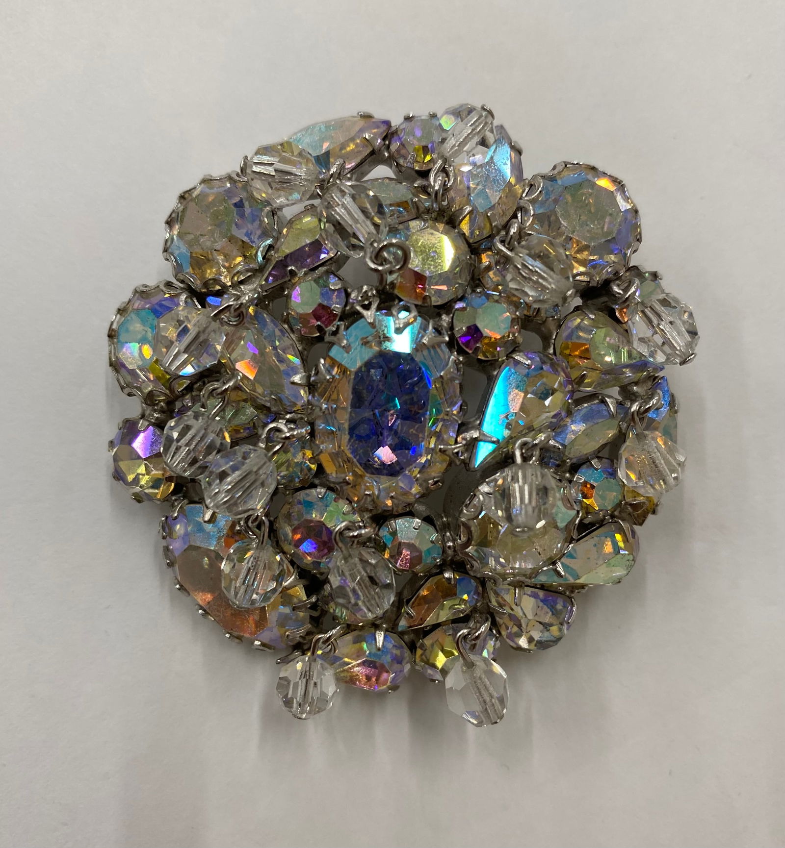 Vintage Aurora Borealis Crystal Cluster Domed Brooch - Mid-Century Iridescent Statement Piece: This stunning mid-century brooch features a high-domed, tiered cluster of shimmering Aurora Borealis (AB) crystals. The arrangement includes a variety of cuts, featuring a prominent central oval