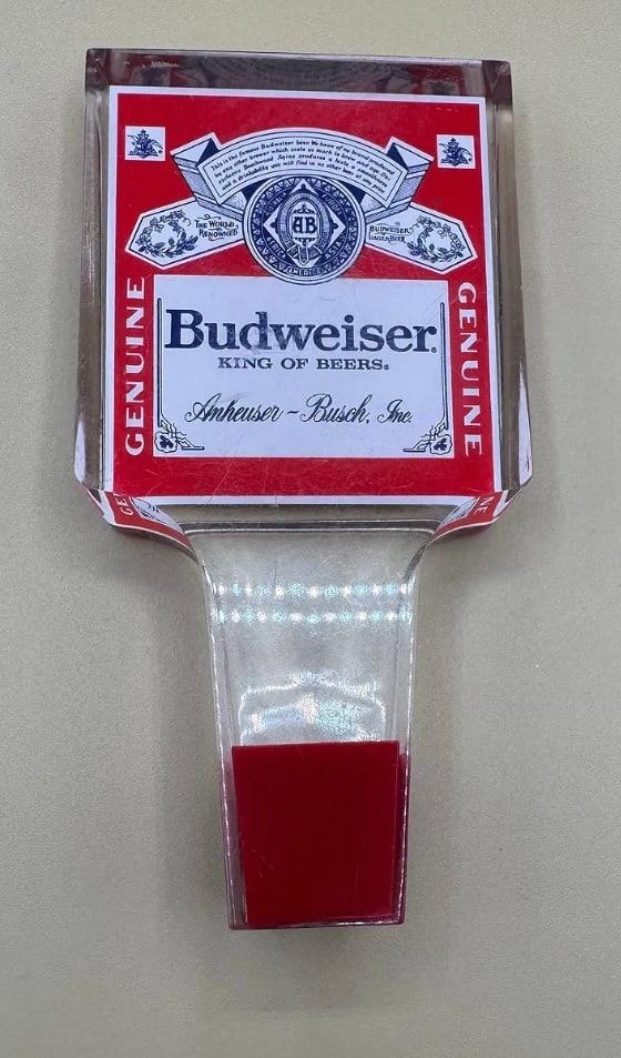 Vintage Budweiser "King of Beers" Rectangular Lucite Tap Handle: A classic 1970s/80s style heavy Lucite tap handle. It features the traditional Budweiser "Bowtie" label branding embedded in clear acrylic. A staple piece for any "King of Beers" collection. • D