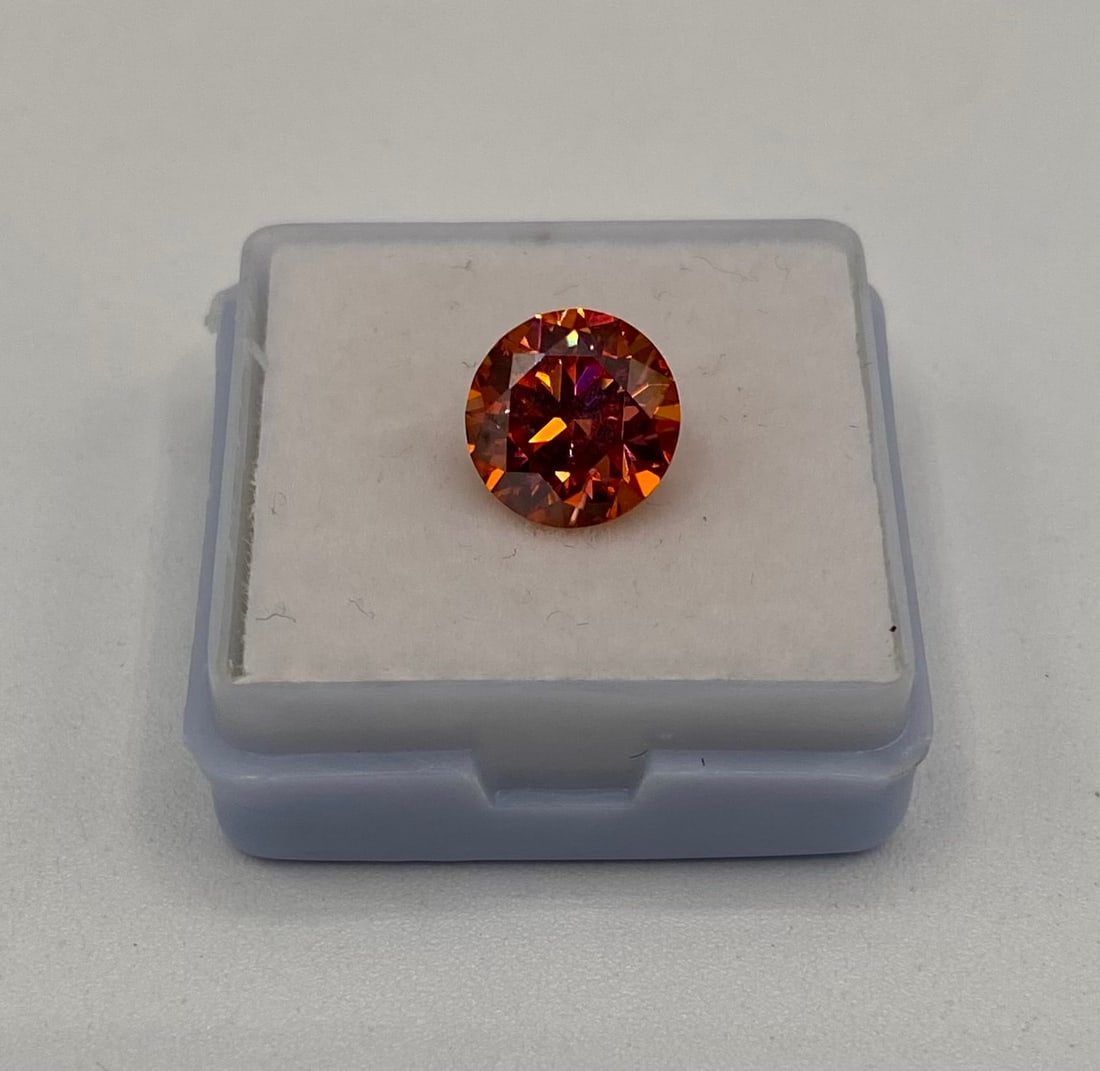 3.00ct Vivid Orange-Cognac Moissanite Round Brilliant Cut - GRA Certified: A bold and fiery 3.00 carat round brilliant cut Moissanite in a striking Vivid Orange-Cognac tone. This gemstone is perfect for high-end custom jewelry, offering an intense saturation of color