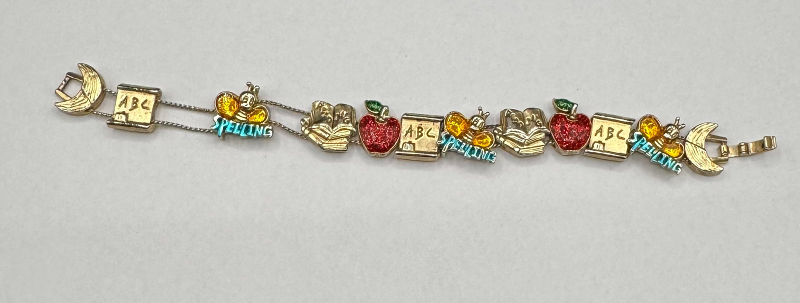 Vintage Gold-Tone School Theme Multi-Charm Link Bracelet - Spelling Bee & ABCs: A charming vintage gold-tone link bracelet featuring a nostalgic schoolhouse/teacher theme. This piece includes colorful enameled and glitter-accented charms including: • "Spelling Bee" charms
