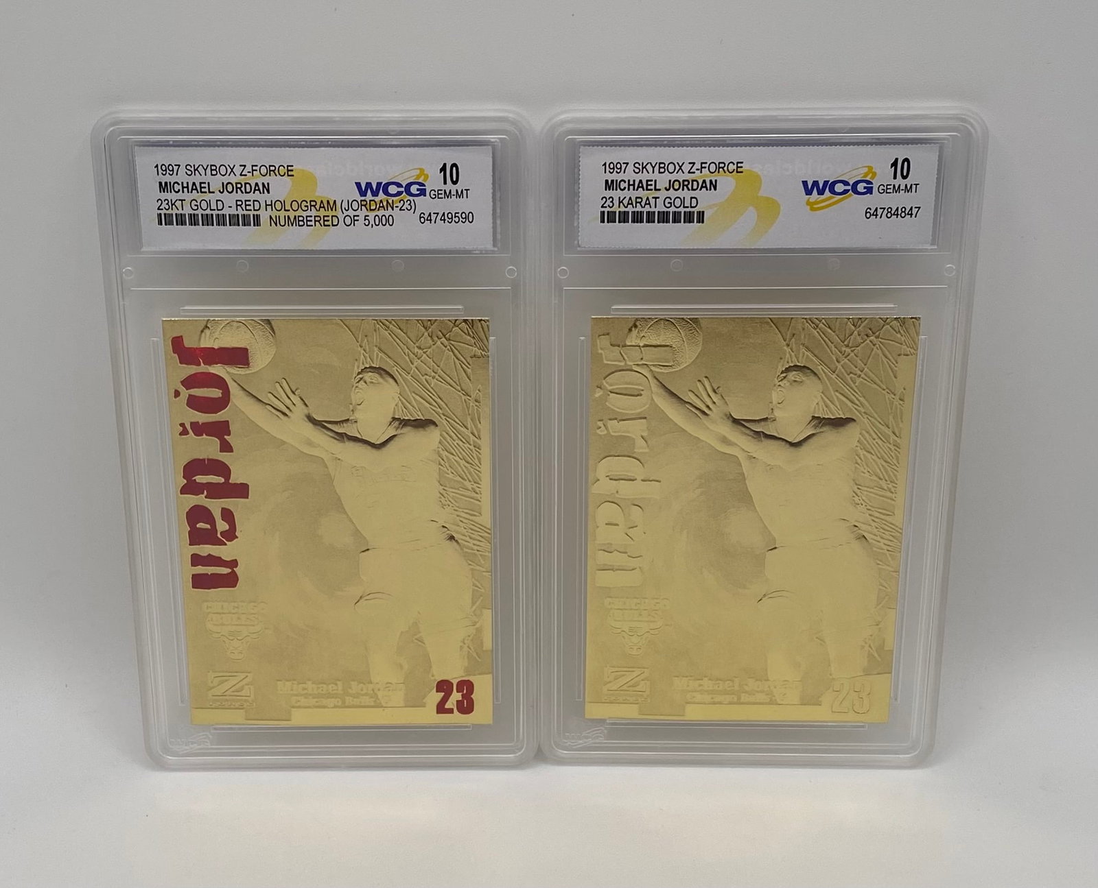 1997 SkyBox Z-Force Michael Jordan 23KT Gold Slabs – Red Hologram & Standard Gold: A premium dual-card lot featuring two gleaming 1997 SkyBox Z-Force Michael Jordan 23-Karat Gold commemorative cards. Both cards showcase an iconic engraved action image of Jordan driving to the hoop. 