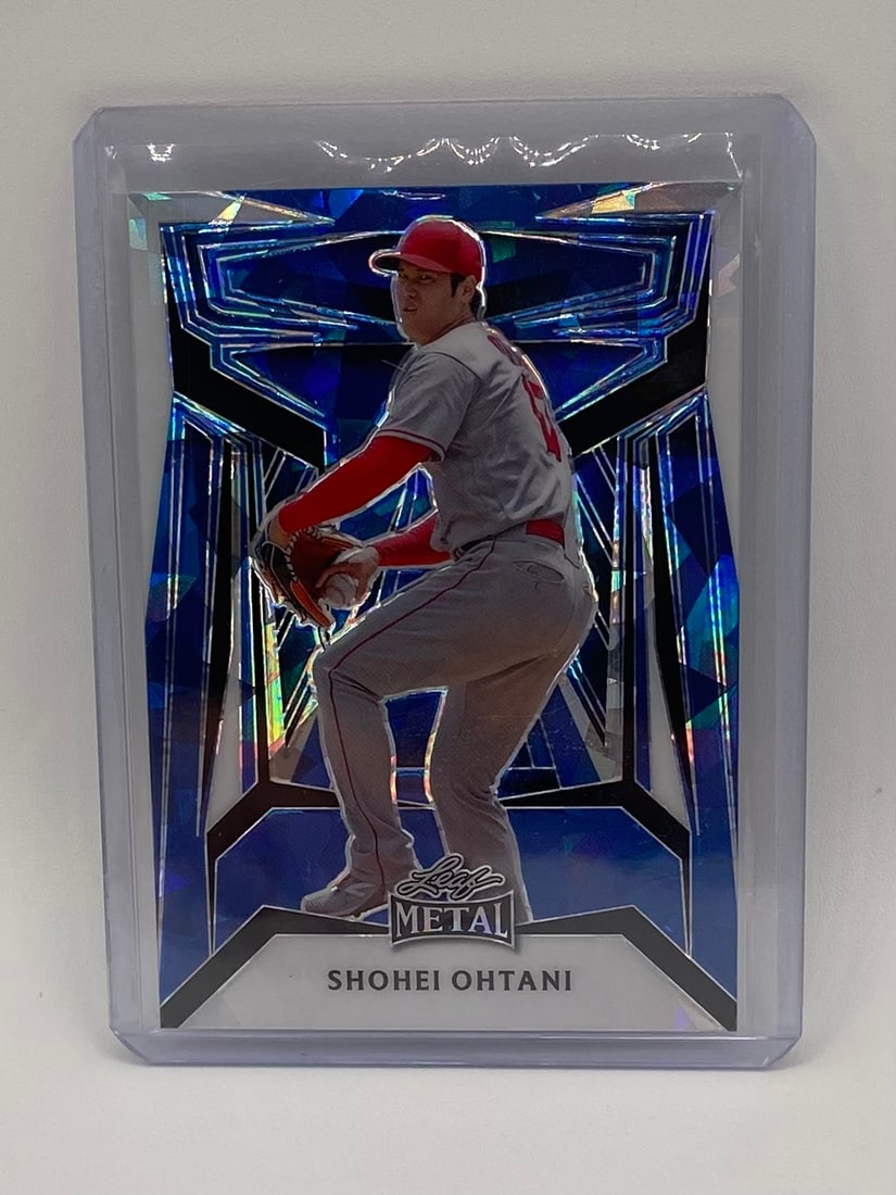 Shohei Ohtani Premium Blue Shimmer/Cracked Ice Foil /7: An eye-catching Leaf Metal insert highlighting Shohei Ohtani on the mound. The card utilizes a high-velocity, geometric blue shimmer/cracked ice laser-foil pattern that frames the superstar pitcher