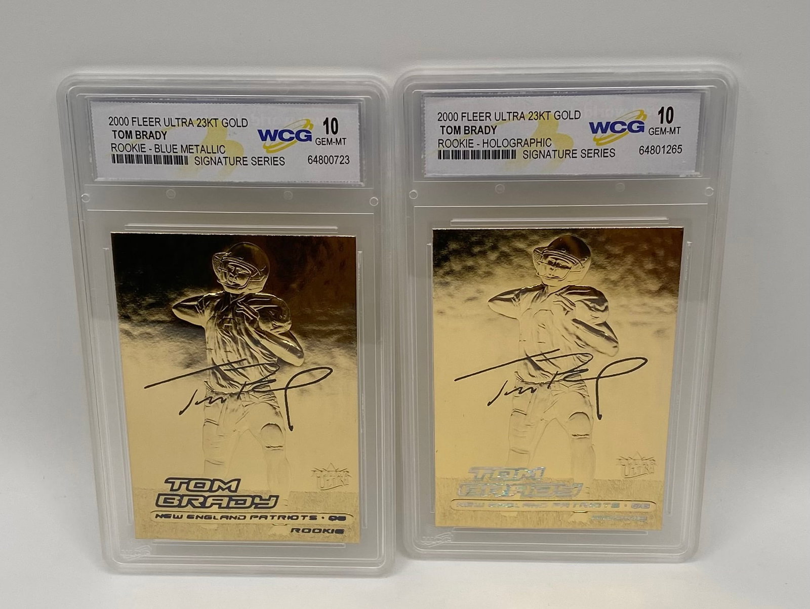 (2) Tom Brady 2000 Fleer Ultra 23KT Gold Rookie Cards: Celebrate the GOAT with two stunning 23 Karat Gold metallic rookie cards commemorating Tom Brady's entrance into the NFL with the New England Patriots. Both cards are graded Gem-MT 10 by WCG. Card 1: 
