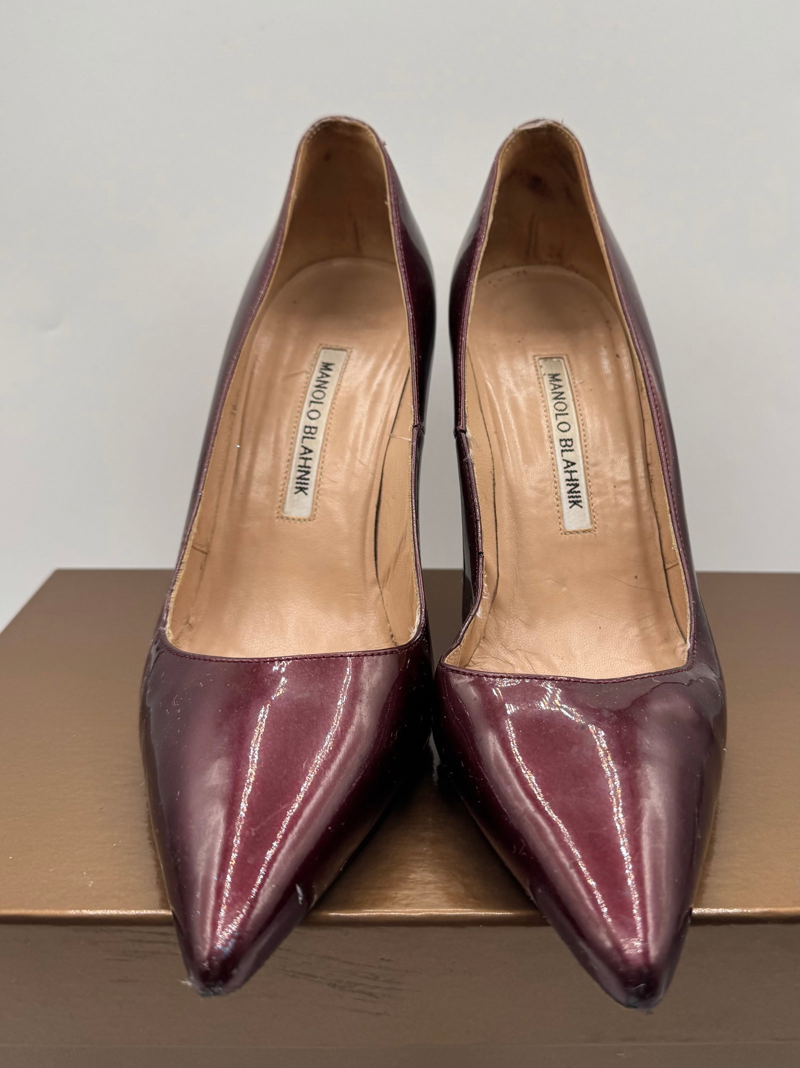Manolo Blahnik Burgundy Patent Leather BB Pump: A classic and sophisticated pair of authentic Manolo Blahnik "BB" pointed-toe pumps. Crafted in Italy, these iconic heels feature a striking deep burgundy (oxblood/bordeaux) patent leather finish that