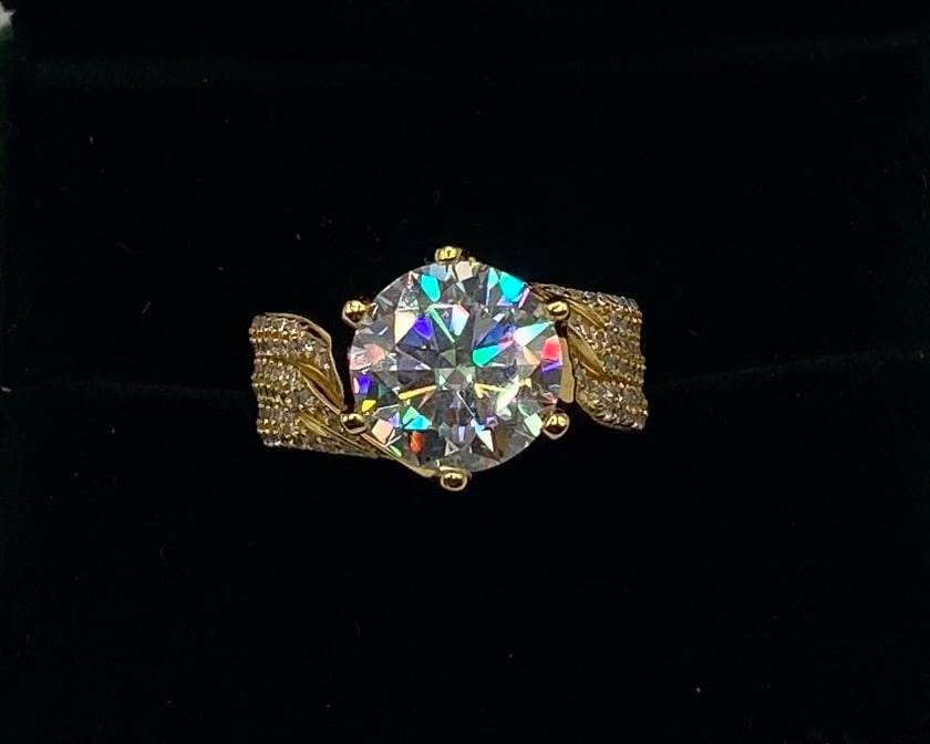 5.00 Ct Round Moissanite Wave Pavé Statement Ring in 18K Yellow Gold Over Silver: Gemstone: Lab-Created Moissanite Carat Weight: Approx. 5.00 Carat Center Stone (Plus Pavé Accents) Cut: Round Brilliant Cut Metal: 18K Yellow Gold Plated over Solid .925 Sterling Silver Ring