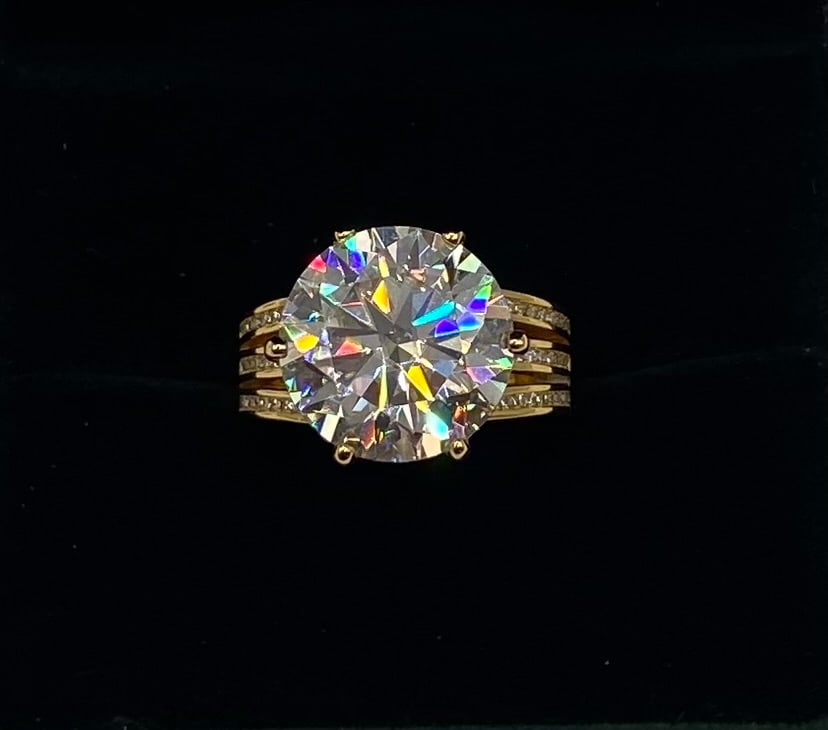 10 CT Round Moissanite Wave Pavé Statement Ring: Gemstone: Lab-Created Moissanite Carat Weight: Approx. 10.00 Carat Center Stone (Plus Pavé Accents) Cut: Round Brilliant Cut Metal: 18K Yellow Gold Plated over Solid .925 Sterling Silver Ring