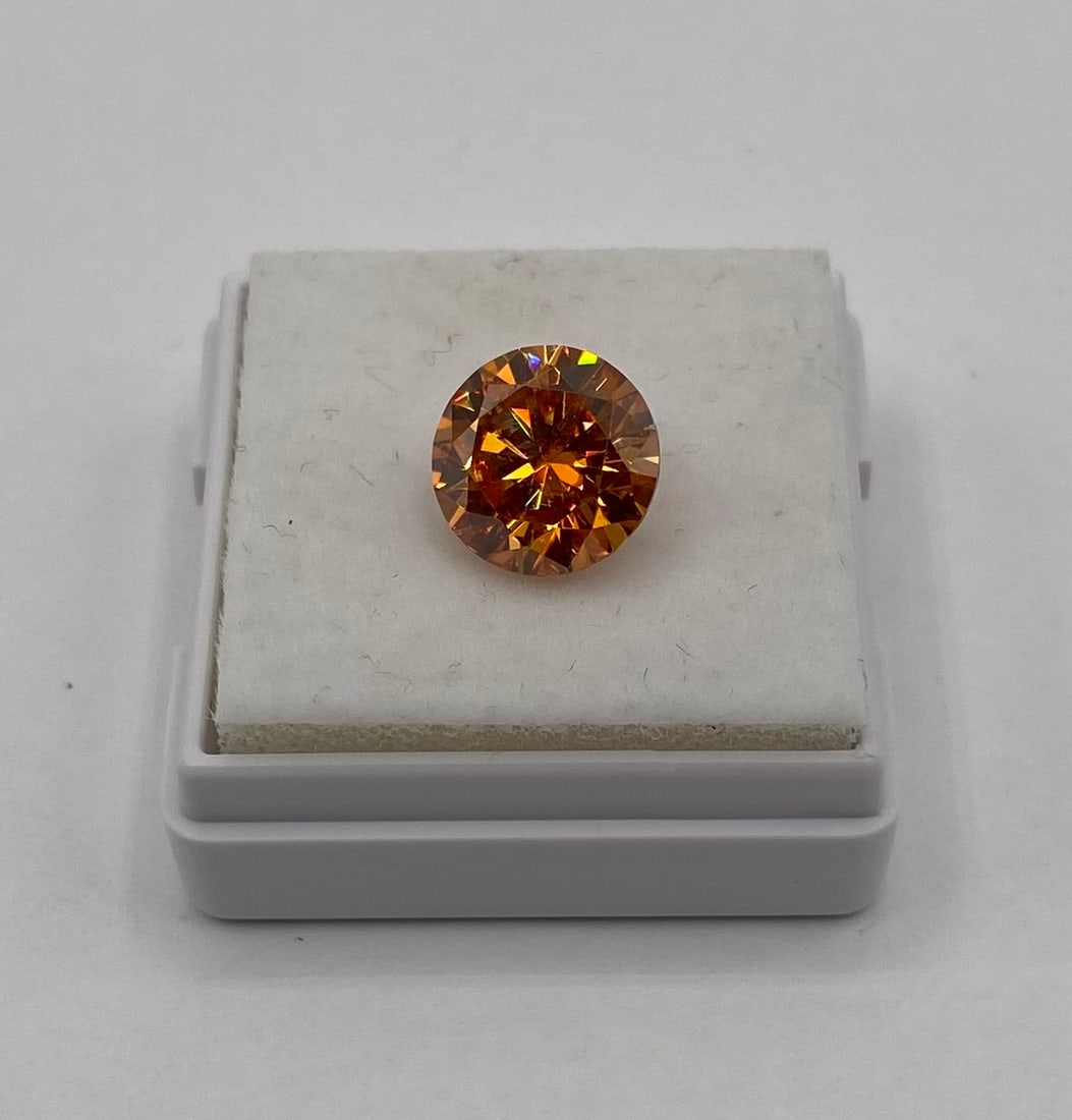 Orange Moissanite Loose Gemstone – W/ GRA Certificate & Passes Diamond Tester: Up for auction is a stunning, loose Moissanite gemstone featuring a rich, fiery cognac-orange hue. Masterfully cut into a brilliant round shape, this 3-carat stone showcases exceptional fire, brillian