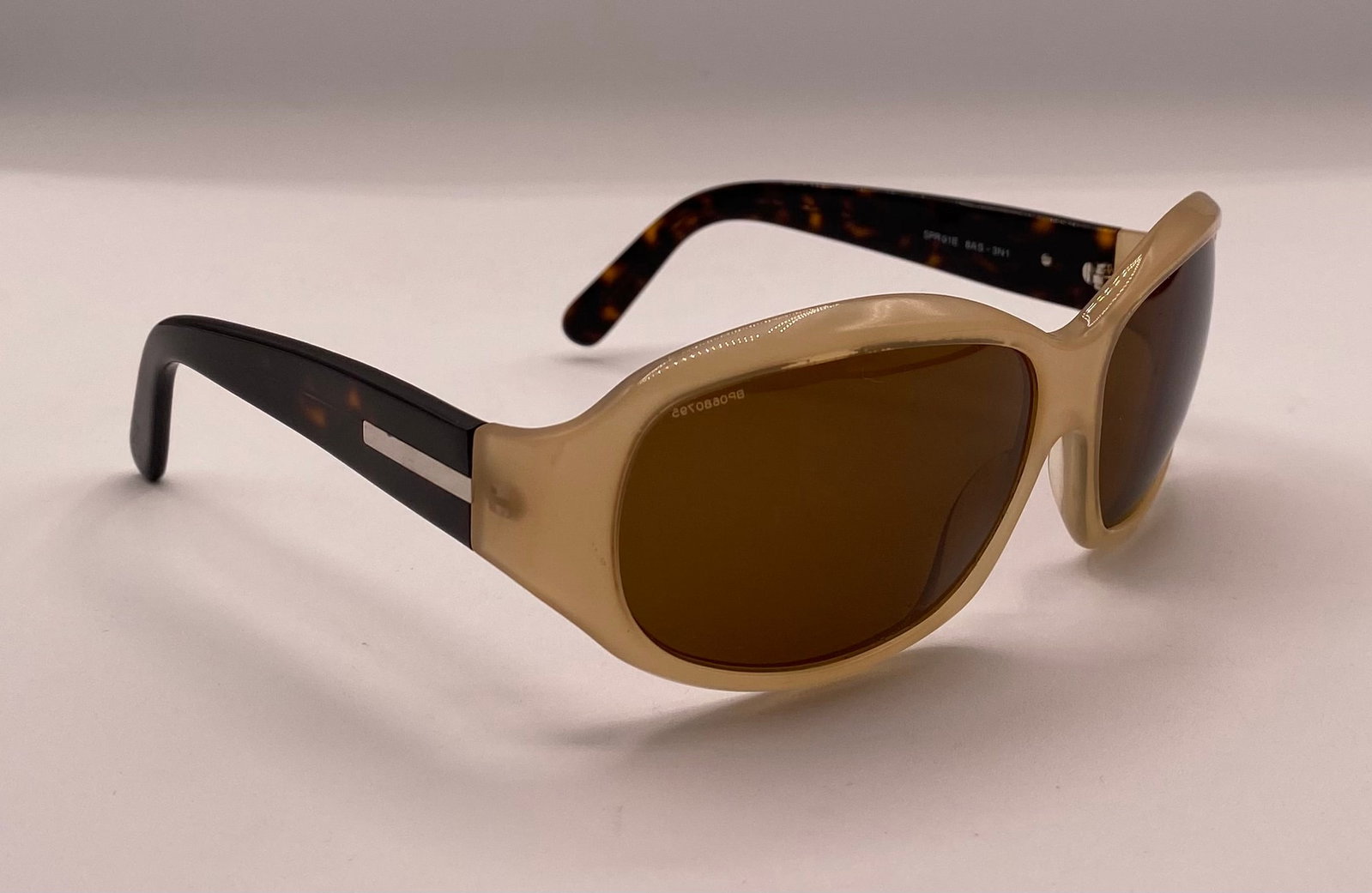 Prada Sunglasses: Up for auction is a pair of authentic pre-owned Prada sunglasses (Model: SPR01E 8AS-3N1). This pair features a distinct two-tone design with a cream/beige oval front frame, classic dark tortoise