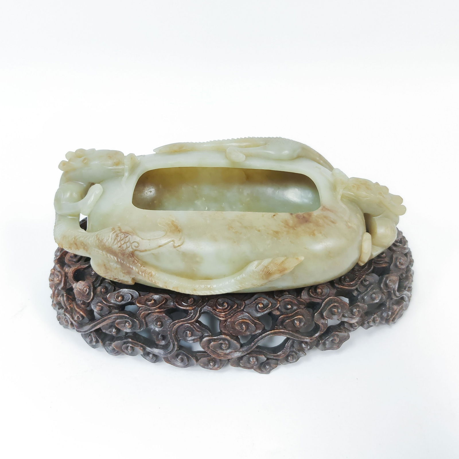 CHINESE ANTIQUE JADE BRUSH WASHER ON STAND: Measures: 3-7/8" H x 9-1/8" L Chinese antique Jade brush washer with two coiling dragon facing the opening. Displayed on carved hardwood stands in clouds motif. Natural Jade. PROVENANCE: William John