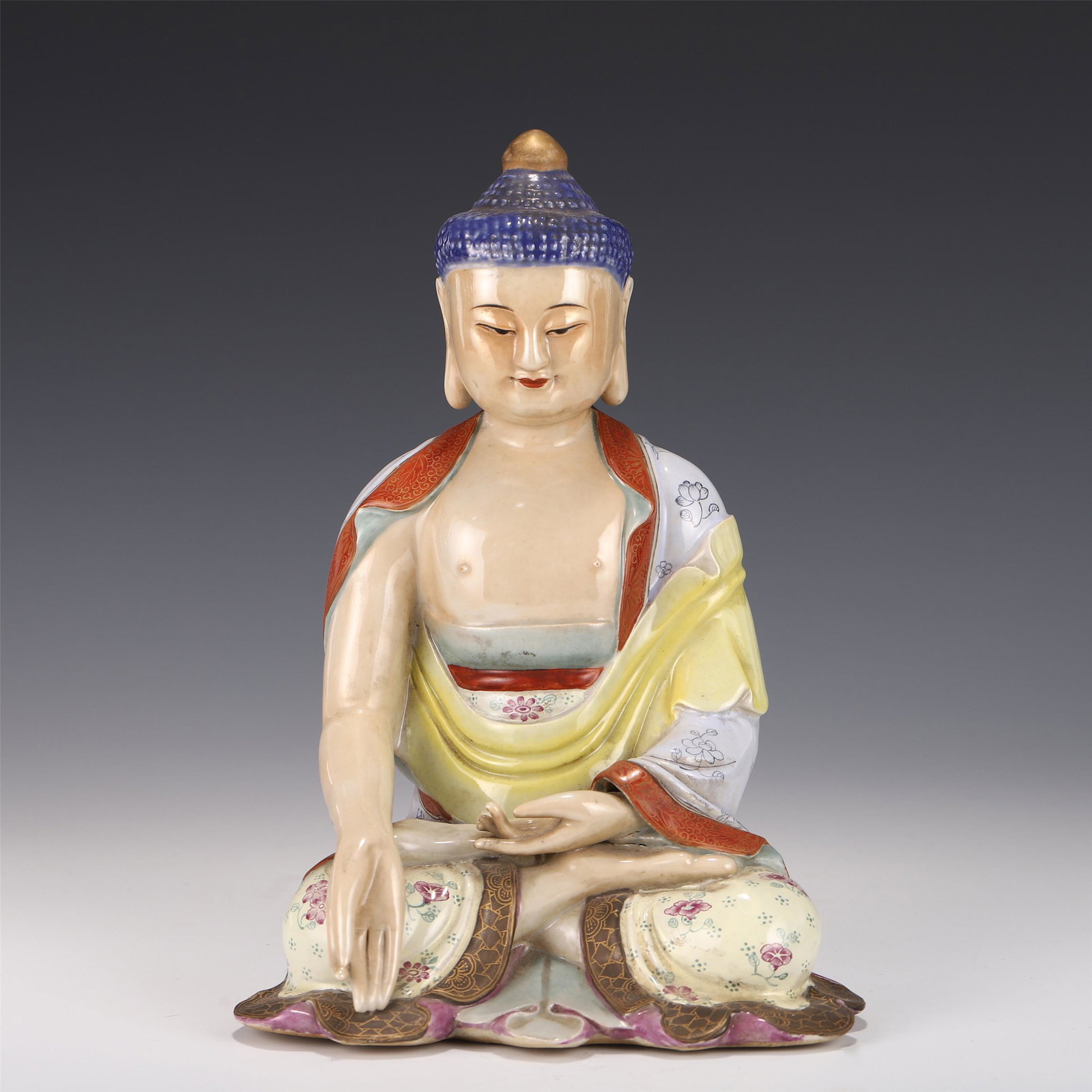 A CHINESE PORCELAIN FIGURE OF BUDDHA: 24.5 cm H x 17.5 cm L x 13 cm WThis porcelain statue has a headdress with snail hair, a round and high-convex bun, and a mani orb on the top. The eyelids are slightly open, the corners of the eyes are