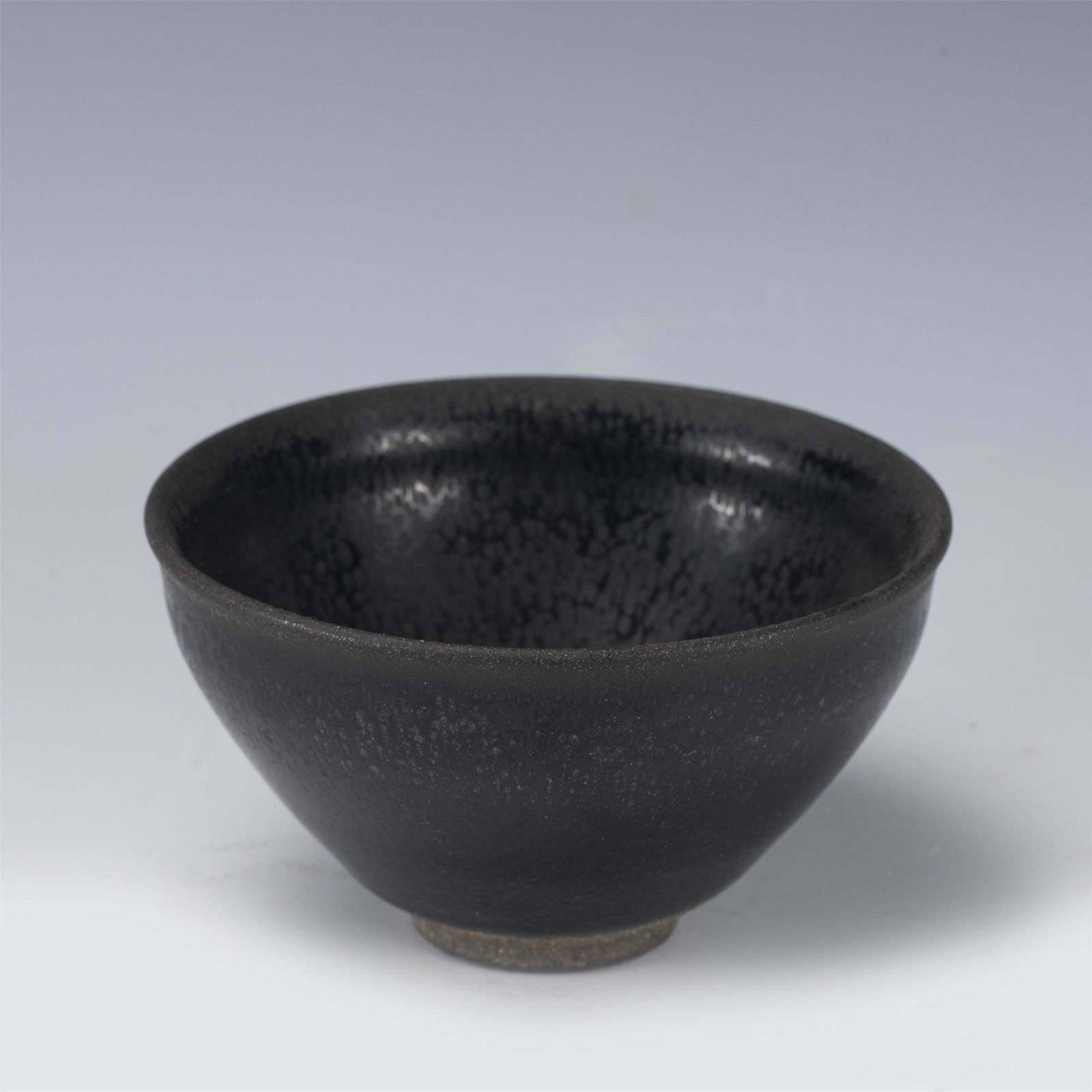 A PORCELAIN JIANYAO CUP,SONG: A PORCELAIN JIANYAO CUP,SONG 12 cm Diam x 7 cm H x Weight 330 gram. The tea bowl is well potted with deep rounded sides rising from a short foot rim rising to a finger-grooved rim, covered with a thic