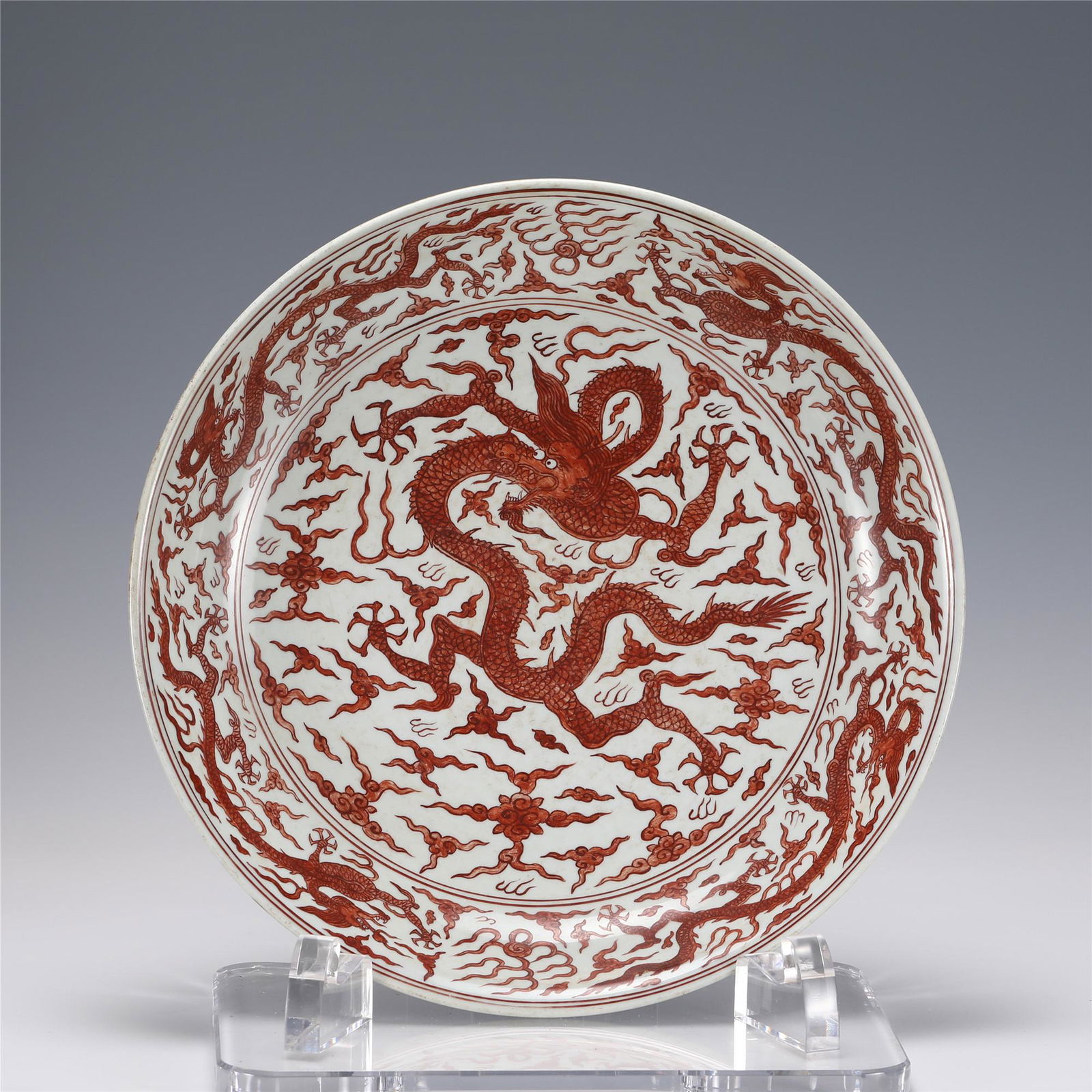 A CHINESE IRON RED GLAZE PORCELAIN DISH,JIAJING: A CHINESE IRON RED GLAZE PORCELAIN DISH,JIAJING 43.3 cm Diam x 8.8 cm H Decorated in the center with a five claws dragon and dragon bands encircling the rim, all in a red tone on a grayish white groun