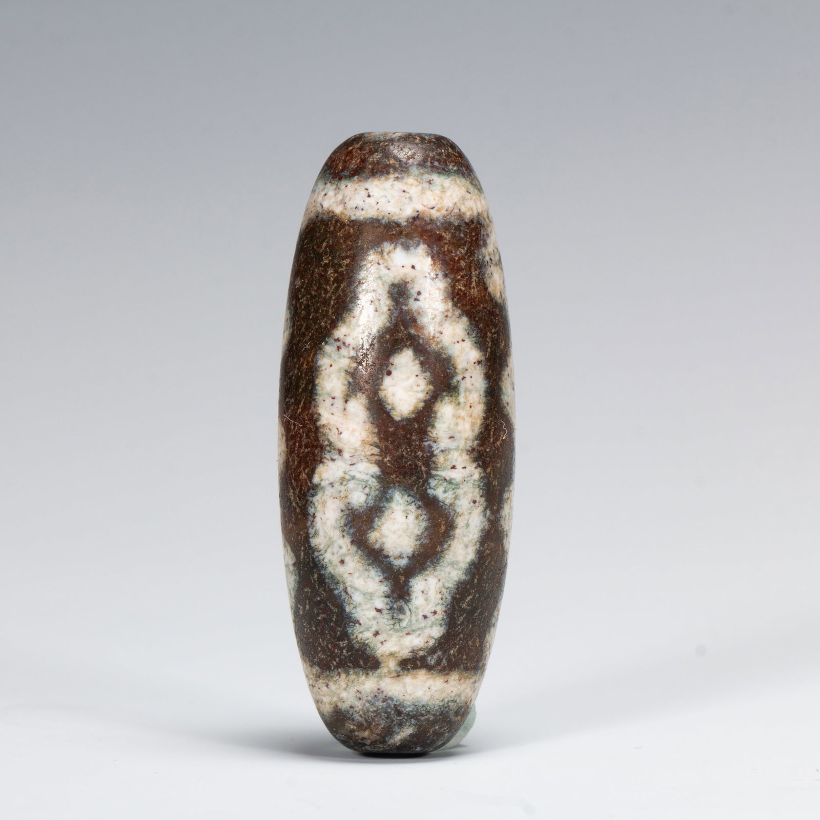 A DZI BEAD: Dimensions: L. 5 cm. Weight 20 grams. This is a Dzi bead. Dzi beads are renowned for their unique patterns. This particular Dzi bead features symmetrical geometric patterns. In Tibetan - Buddhist cult