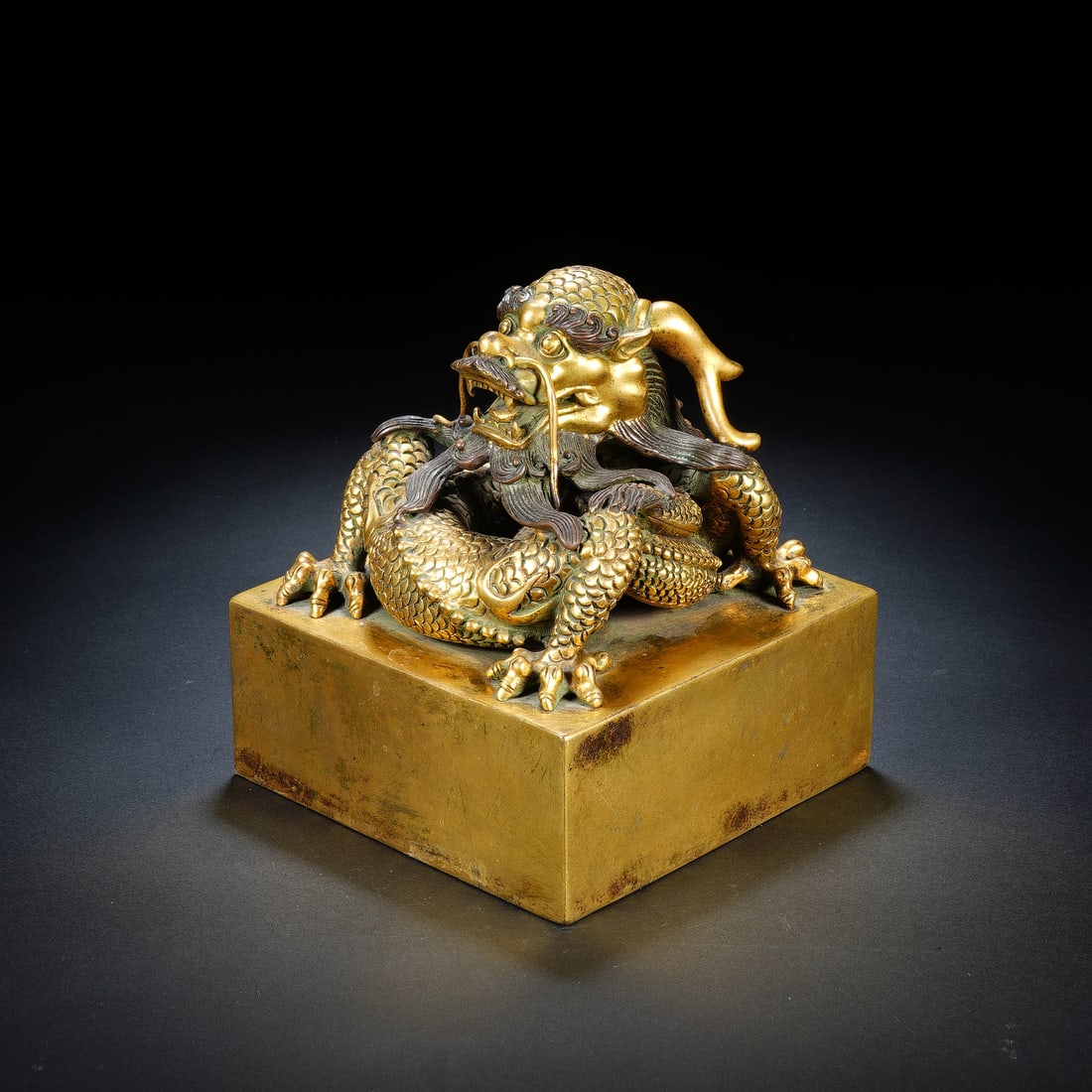 A CHINESE GILT-BRONZE DRAGON SEAL: Dimensions:13.5x13.5x15 cm. Weight 5600 grams. This is a finely cast Qing dynasty Chinese gilt-bronze seal, topped with a dynamic coiled dragon finial. The dragon is rendered with detailed scales,