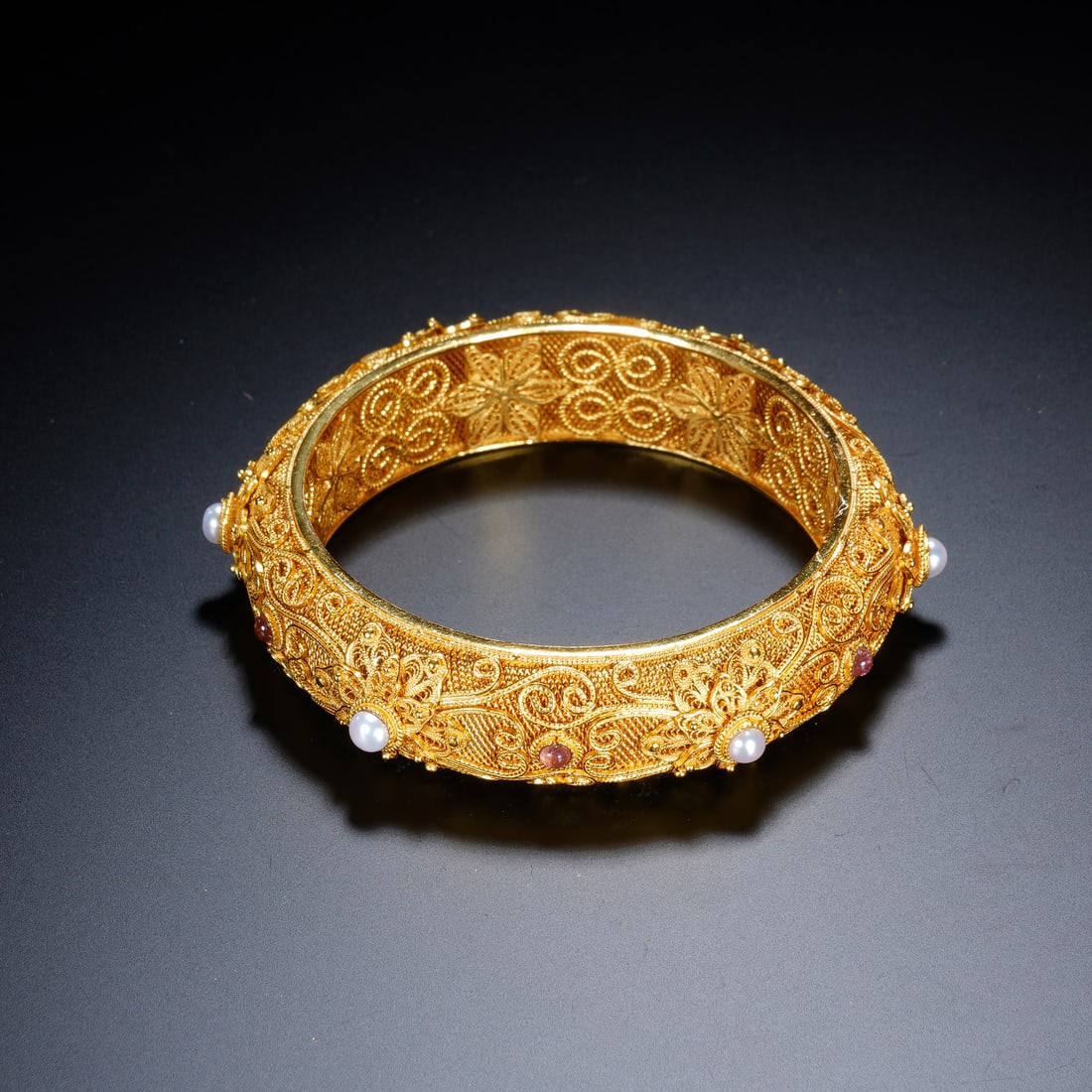 CHINESE GILT-SILVER GEMSTONE BANGLE: Dimensions:Diam. 5.7 cm. Diam. 7.5 cm. Weight 47 grams. A fine Chinese gilt-silver bangle bracelet, crafted in the Filigree technique with an intricate openwork pattern of scrolling floral and