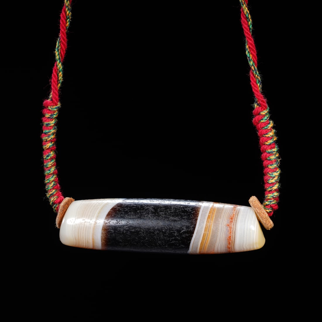 CHINESE ANTIQUE BANDED AGATE DZI BEAD: Dimensions:L. 5.7 cm. Weight 22 grams. A fine Chinese Qing dynasty antique dzi bead pendant, crafted from banded agate with striking layered patterns of creamy white, warm honey, and deep black.