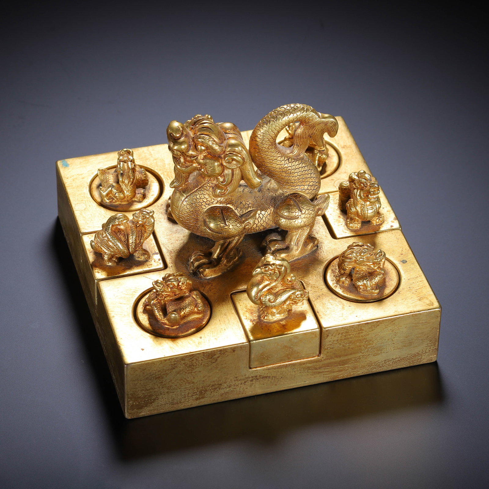 CHINESE GILT-BRONZE QILIN SEAL SET: Dimensions:L. 13 cm. W. 13 cm. H. 8 cm. Weight 4670 grams. A fine Chinese set of gilt-bronze seals, centered on a large square base crowned with a dynamic qilin finial, surrounded by eight smaller