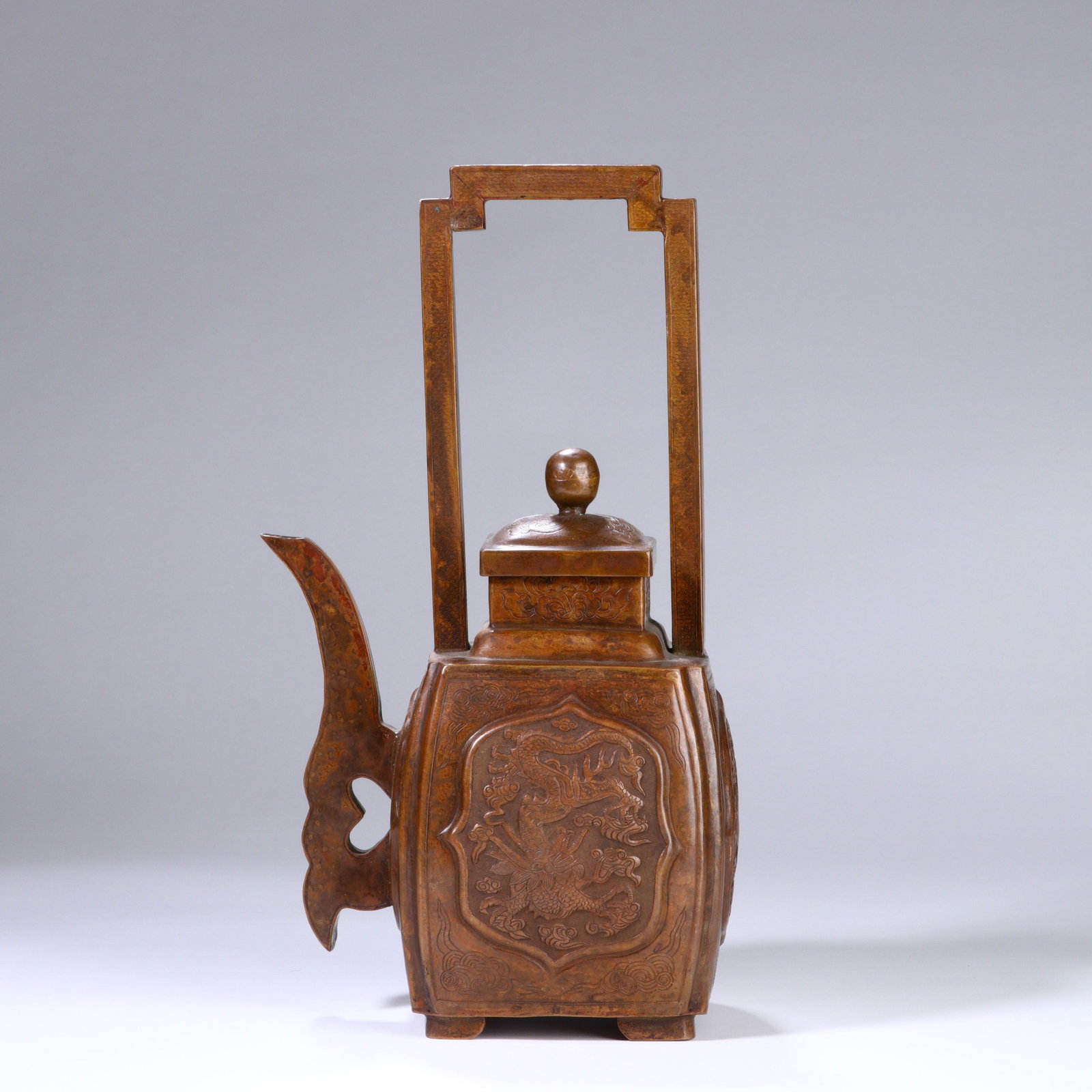 A CHINESE DRAGON-PHOENIX COPPER EWER: Dimensions:29x14.5 cm. This Chinese copper ewer features a tall rectangular handle and a curved, stylized spout, with a warm aged patina that highlights its craftsmanship. The main body is