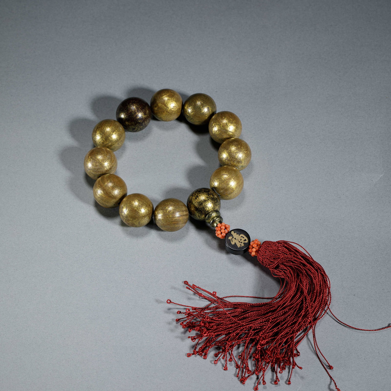 A CHINESE GILDED AGARWOOD PRAYER BEADS: Dimensions:Bead diam. 2 cm. Weight 65 grams. This elegant Chinese prayer bead strand is composed of twelve spherical gilded agarwood beads, each 2 cm in diameter, showcasing a rich golden sheen