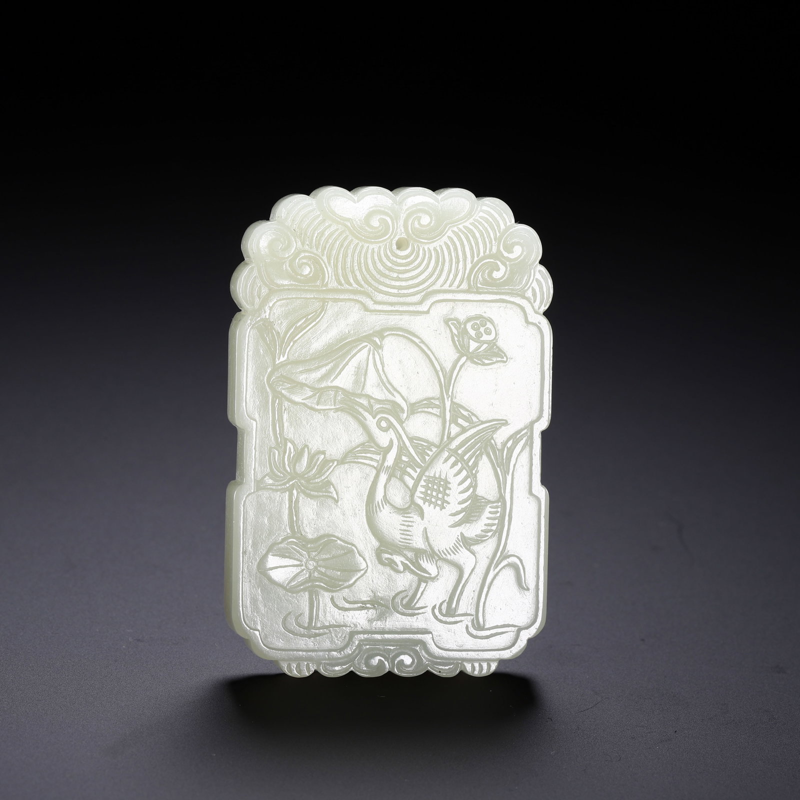 CHINESE WHITE JADE CRANE & LOTUS PLAQUE: Dimensions:L. 6 cm. W. 4 cm. Weight 50 grams. A fine Chinese white jade plaque, carved in the form of a huabiao-shaped plaque with ruyi cloud carvings at the top. The main body is intaglio carved with