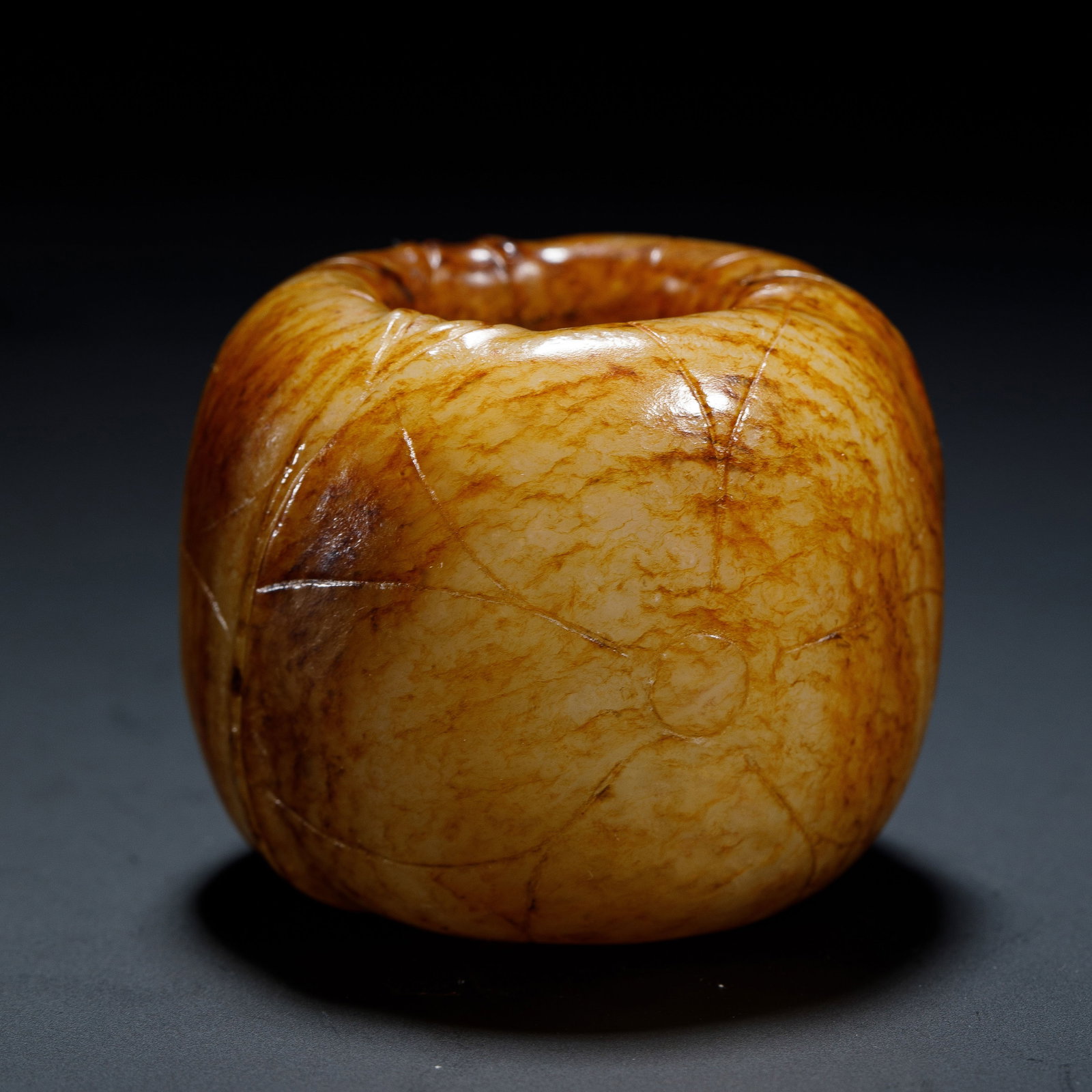 A CHINESE HETIAN JADE ARCHER’S RING: Dimensions:L. 4.7 cm. H. 4 cm. Internal diameter. 2.2 cm. Weight 130 grams. A Chinese archer’s ring carved from warm honey-toned Hetian jade, featuring a rounded, robust form with incised