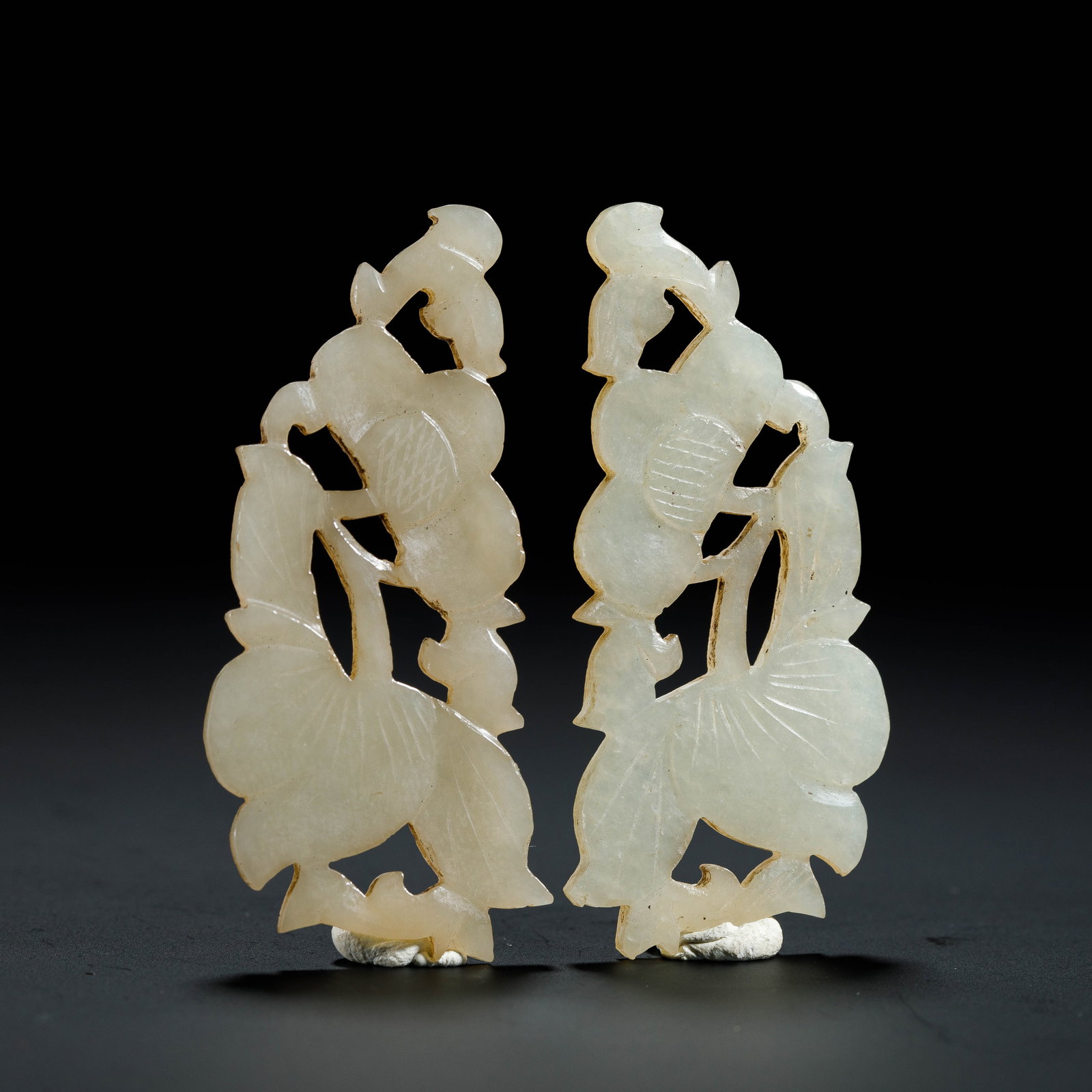 A PAIR OF CHINESE HETIAN JADE FLORAL PENDANTS: Dimensions:L. 2.9 cm. H. 5.5 cm. Weight 13 grams. A pair of Chinese pendants carved from pale white Hetian jade, featuring openwork floral and foliate motifs with delicate incised vein details.