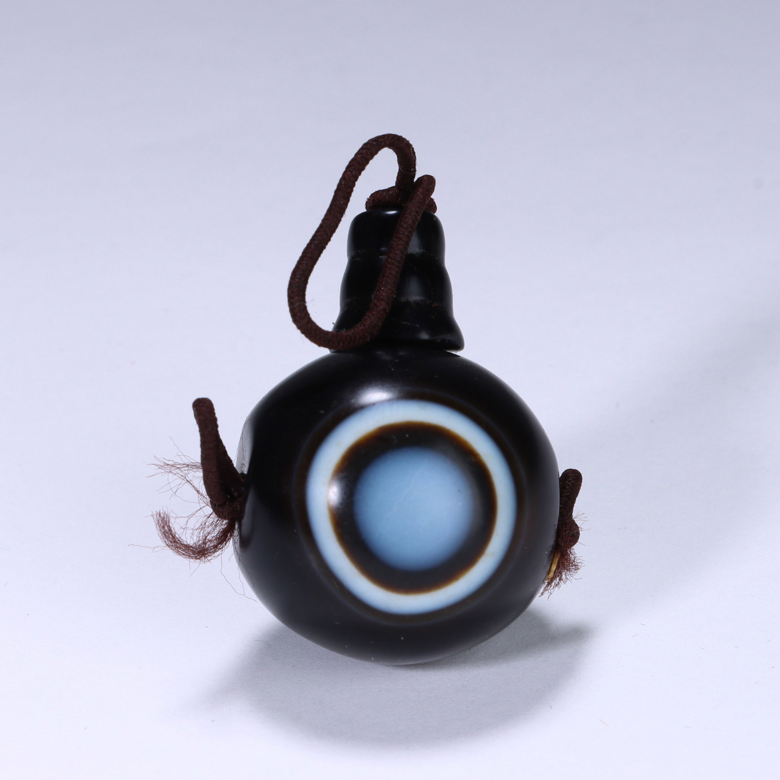CHINESE SINGLE EYE AGATE DZI BEAD: Dimensions:L. 2.6 cm. A Chinese spherical Dzi bead, measuring 2.6 cm in length, crafted from dense, glossy black agate. The bead is distinguished by a prominent central "single eye" motif,