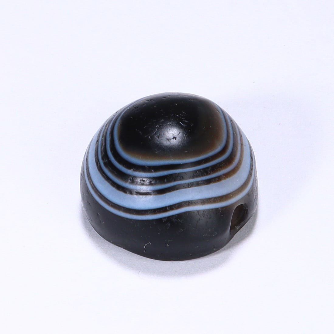 CHINESE NATURAL EYE AGATE DZI BEAD: Dimensions:L. 2 cm. A Chinese domed Dzi bead, measuring 2 cm in length, crafted from naturally banded agate. The bead is distinguished by a striking concentric "eye" motif, featuring a deep black