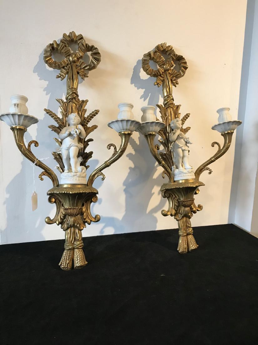 A PAIR OF GILDED METAL CANDLE SCONCES WITH PORCELAIN: A PAIR OF GILDED METAL CANDLE SCONCES WITH PORCELAIN CHERUBS, 24" TALL
