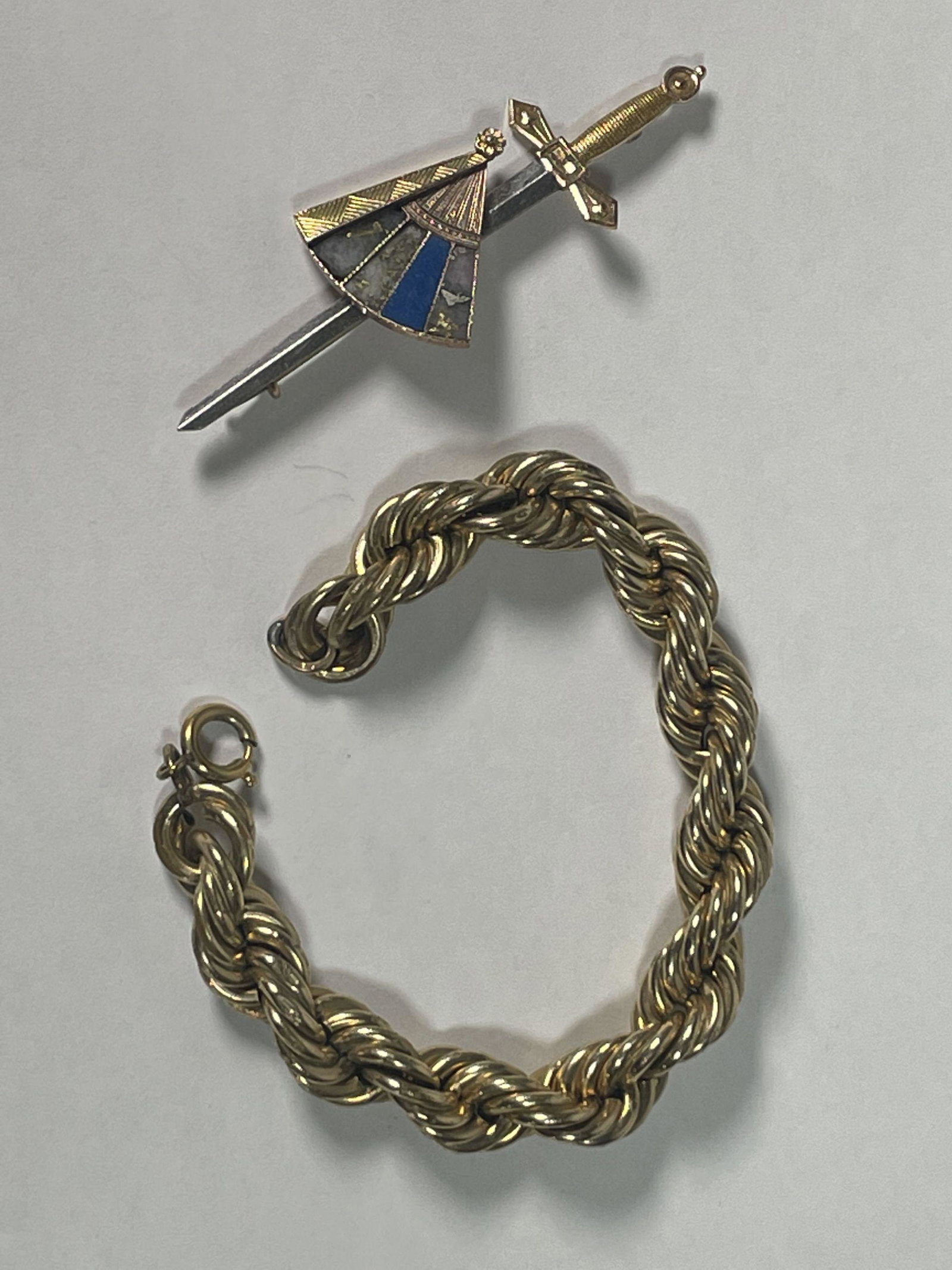 A 10K GOLD SWORD AND FAN PIN AND A GOLD FILLED BRACELET, PIN WEIGHS 6 GRAMS: A 10K GOLD SWORD AND FAN PIN AND A GOLD FILLED BRACELET, PIN WEIGHS 6 GRAMS