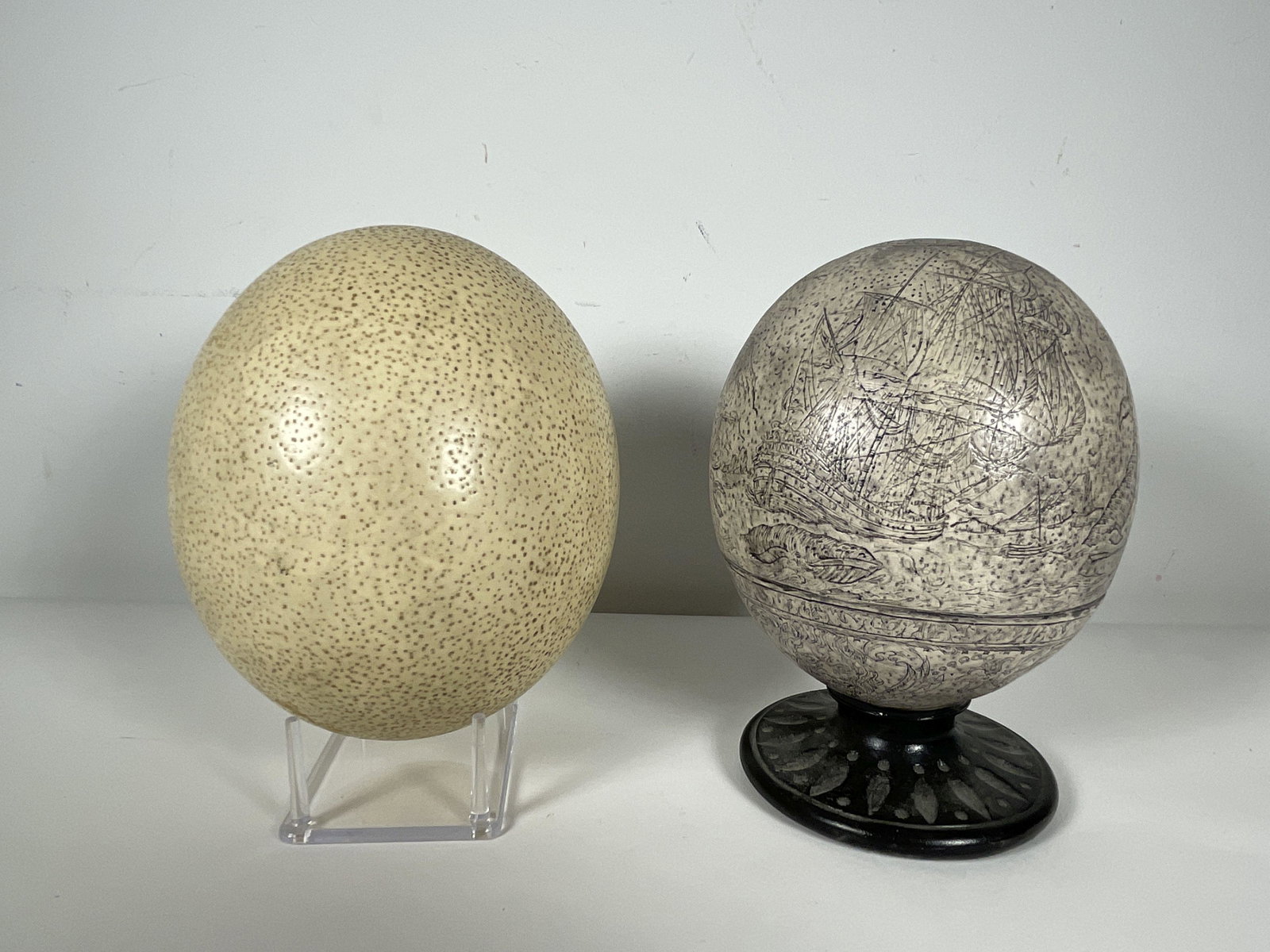 AN INCISED OSTRICH EGG AND AN OSTRICH EGG, 7" X 4" AND 6" X 5": AN INCISED OSTRICH EGG AND AN OSTRICH EGG, 7" X 4" AND 6" X 5"