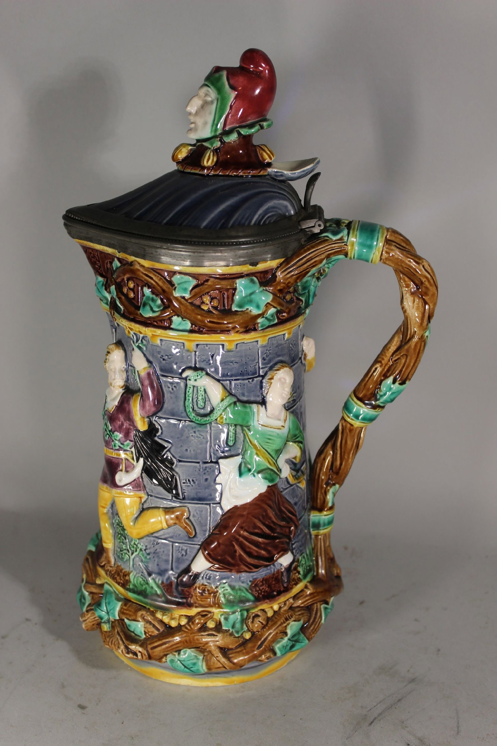 MINTONS MAJOLICA FLAGON TALL LIDDED PITCHER, HAVING DANCING FIGURES 13 1/2" TALL x 8" WIDE.: MINTONS MAJOLICA FLAGON TALL LIDDED PITCHER, HAVING DANCING FIGURES 13 1/2" TALL x 8" WIDE.