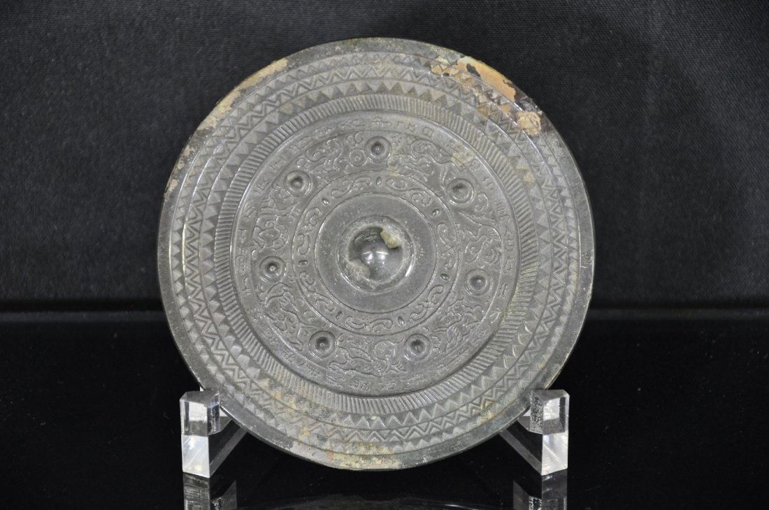 CHINESE METAL MIRROR: Metal Chinese mirror, carved with layered designs and a middle ring of Chinese characters, large handle in the middle. 5.25"D