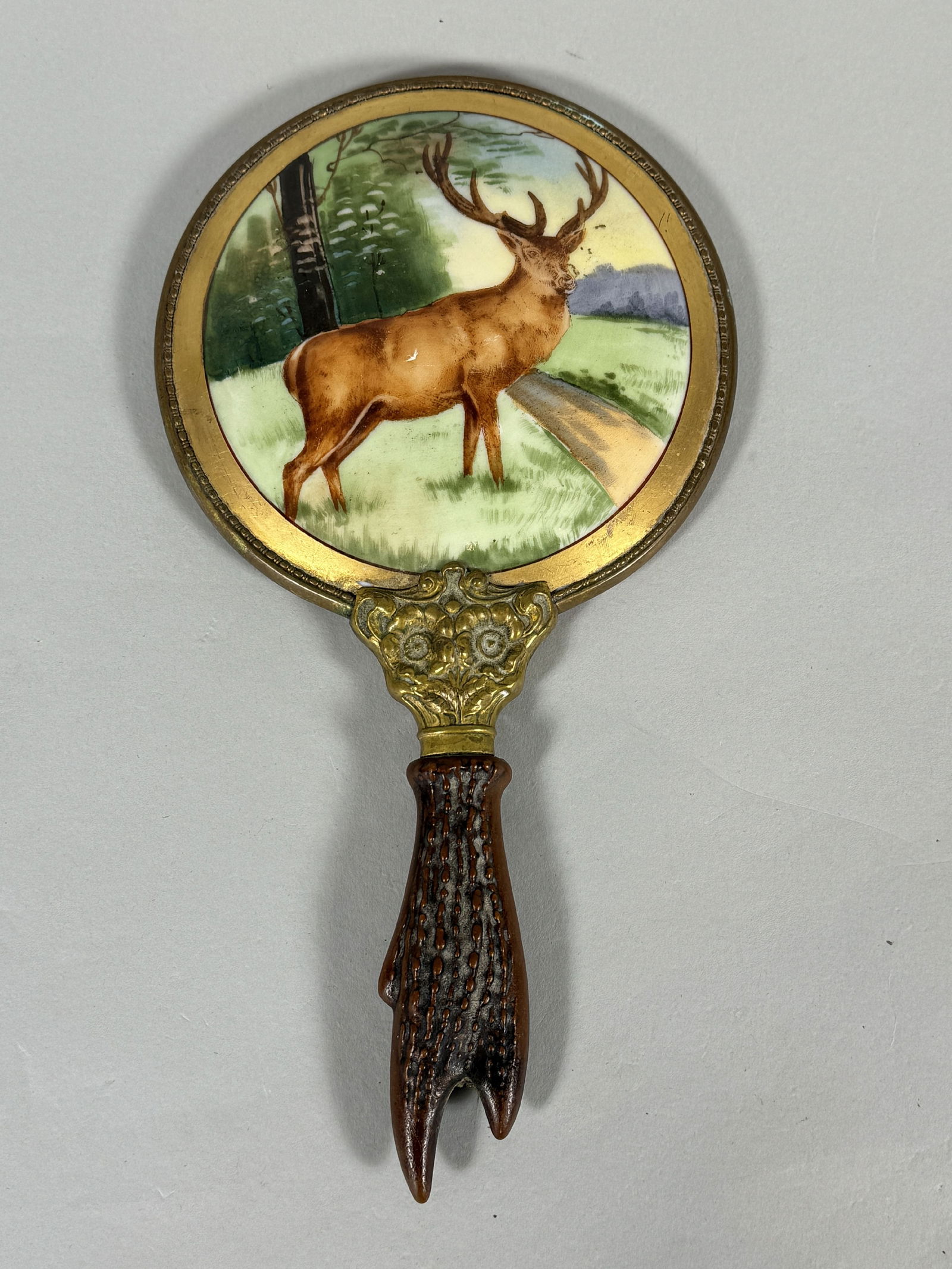 A VICTORIAN STAG HANDLE HAND MIRROR WITH HAND PAINTED BACK ON PORCELAIN, 5" DIAMETER X 9.5" (1 of 2)