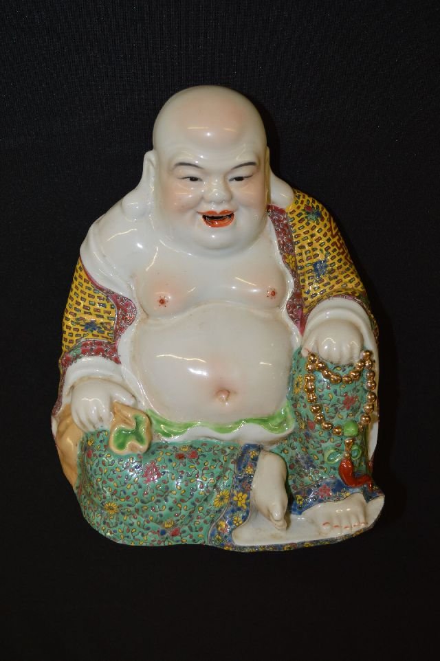 famille rose porcelain figure: Porcelain statue, sitting with left knee raised, left hand resting on knee holding prayer beads, right hand resting on thigh holding a bag, eight carved characters marked on base. 8.5"T