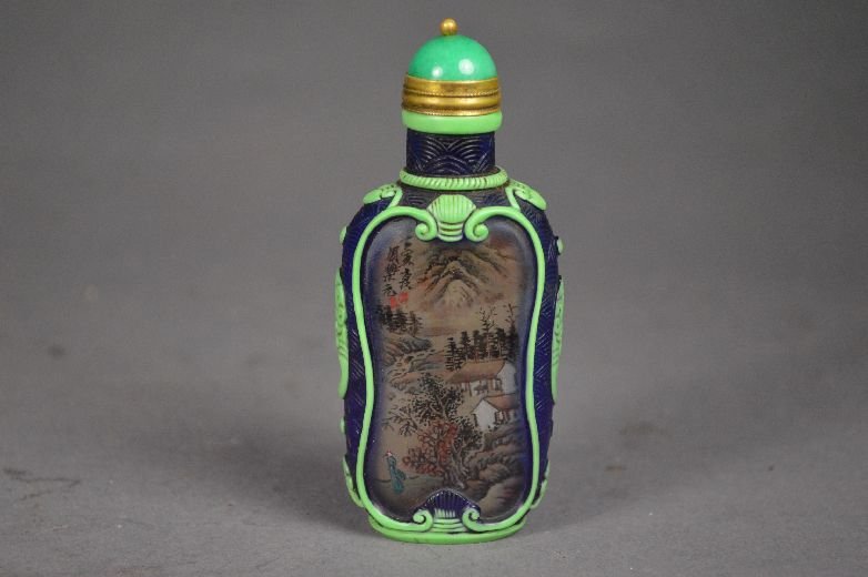 Reverse painting on carved Peking glass snuff b: Peking glass snuff bottle, early 20 th c. reversed painting on Peking glass, an green borders and floral designs on the side, signed by Zhou leyuan. from a private collector Potsdam. VT. 3 1/2"
